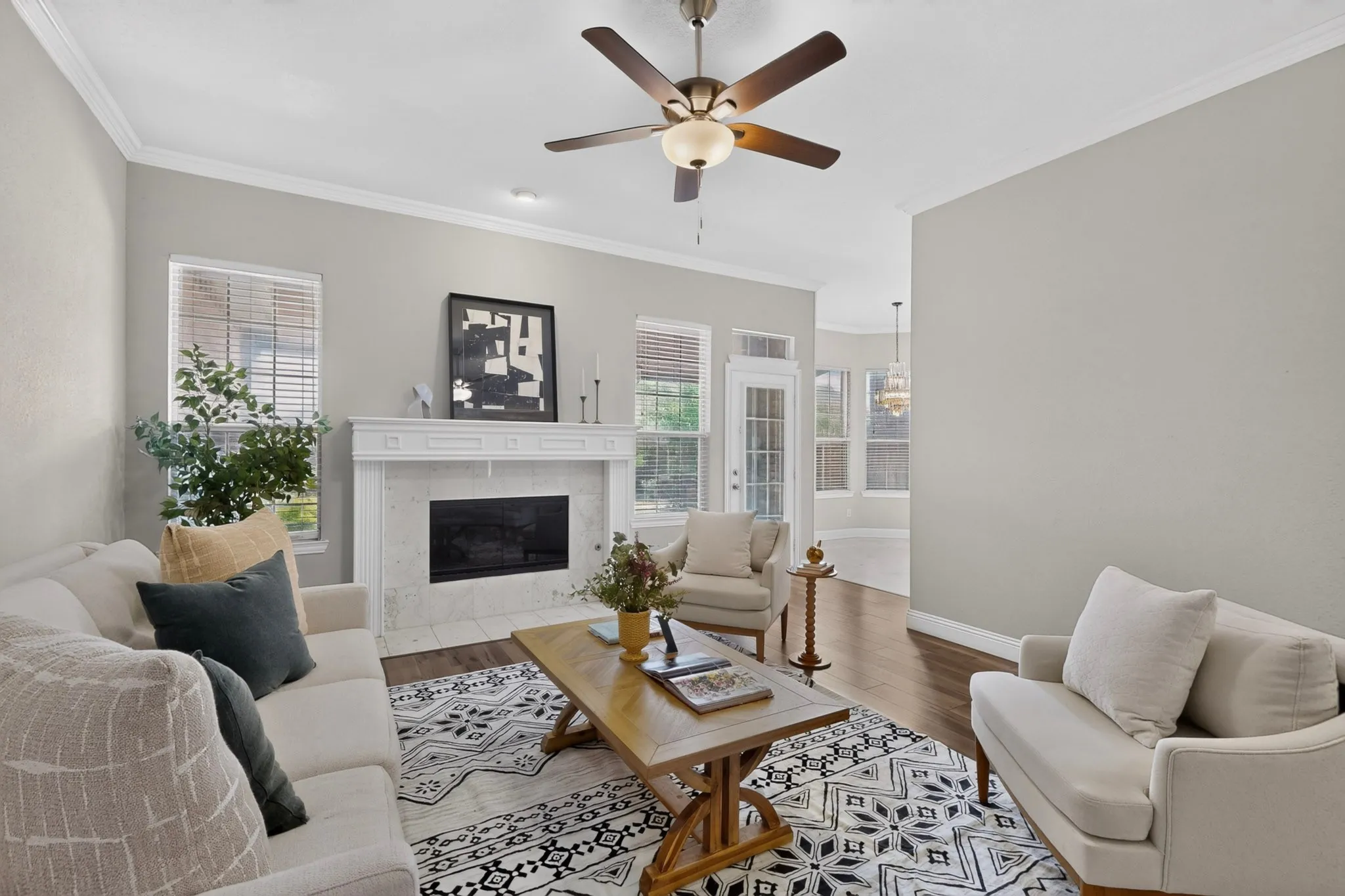 Living area featuring wood-finish flooring, a decorative fireplace with a tile surround and mantel, and crown molding