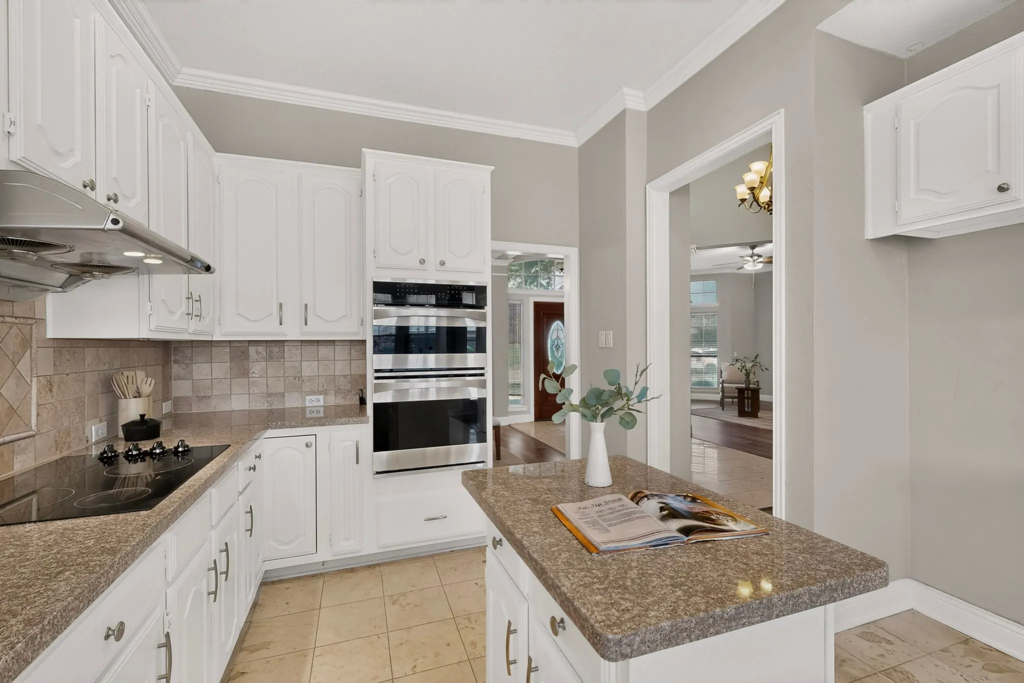Kitchen featuring white cabinetry, built-in stainless steel double ovens, a cooktop with an overhead range hood, and tile flooring