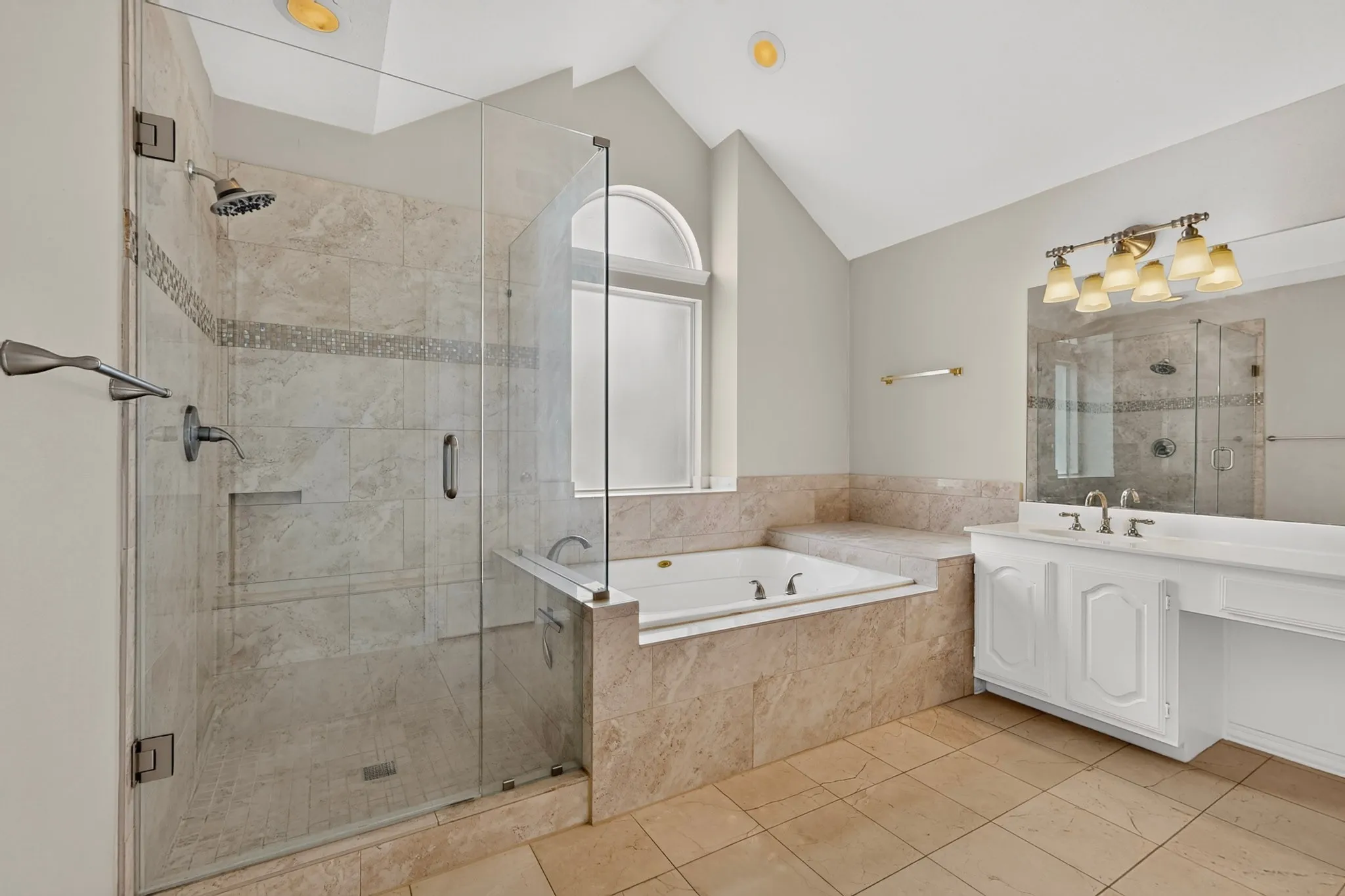 Bathroom featuring a glass-enclosed shower with tile surround, a built-in jetted tub with tile surround, a vanity with dual sinks, a large mirror, and tile flooring