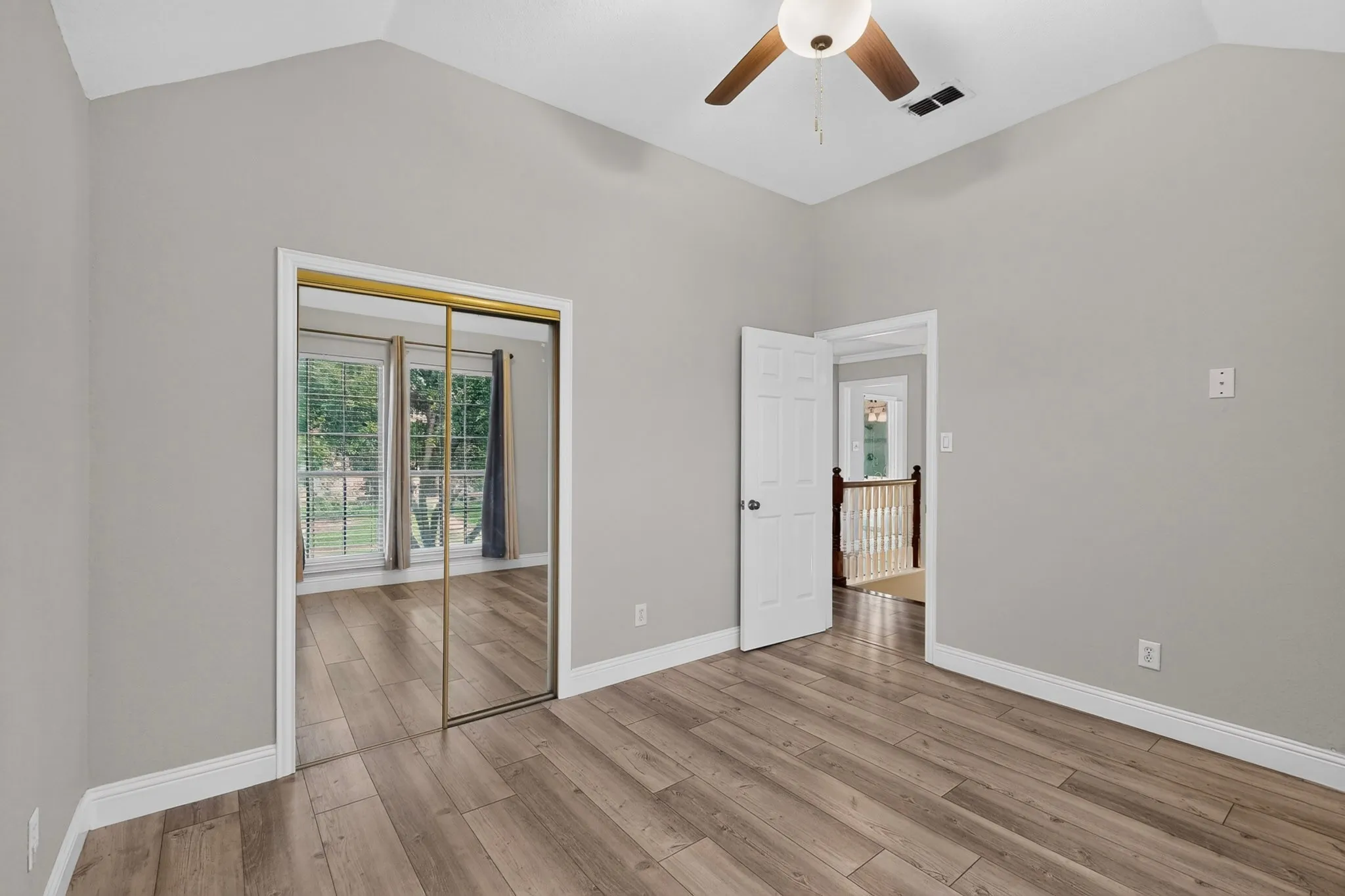 Room featuring vaulted ceilings, wood-finish flooring, and a ceiling fan