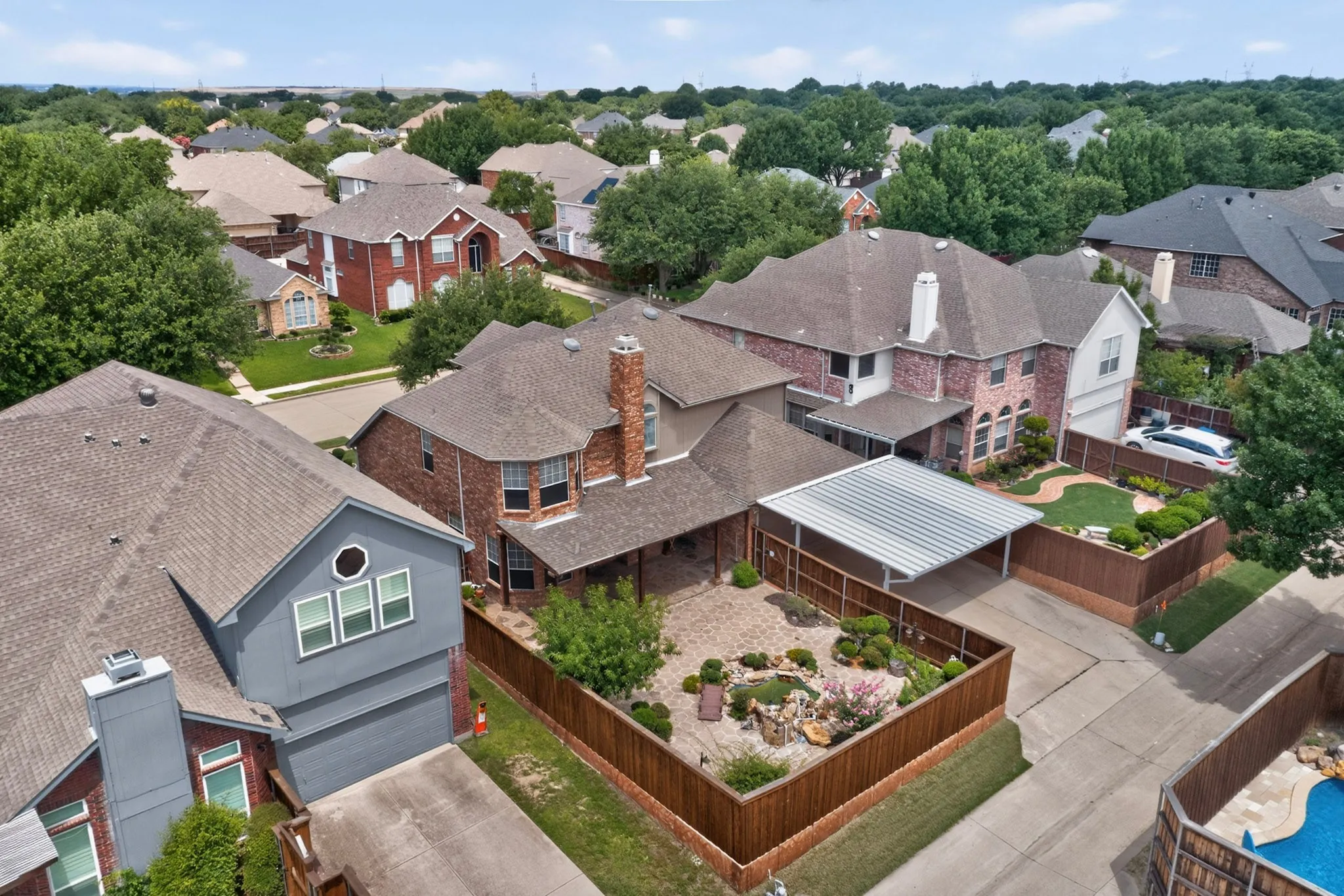 Expansive backyard featuring a stone patio, mature landscaping, and a wooden privacy fence