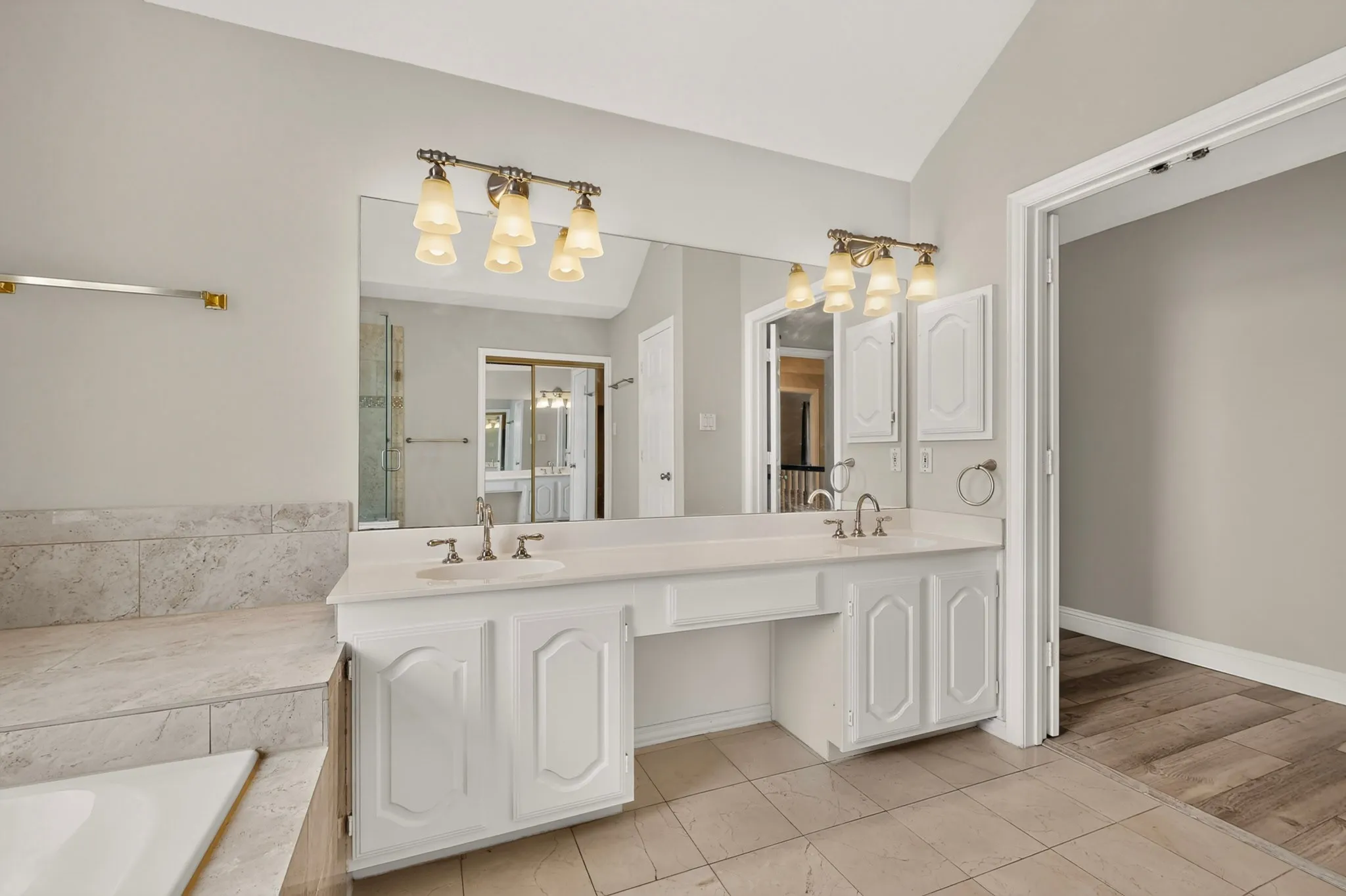 Bathroom featuring a double vanity with integrated sinks, white cabinetry, and a large wall-mounted mirror