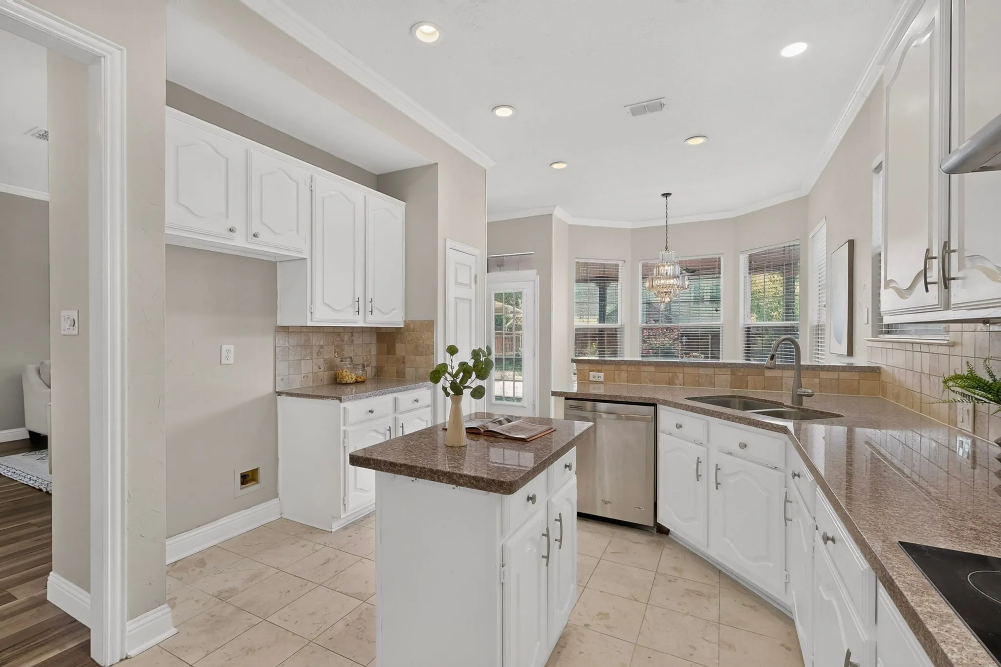 Well-appointed kitchen featuring white cabinetry, stone-finish countertops, and a tiled backsplash