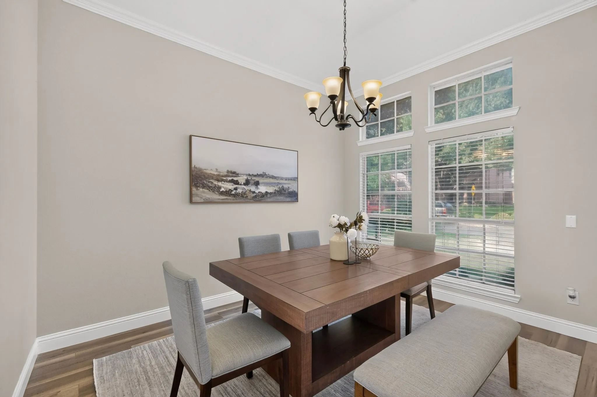 Vaulted ceiling dining area featuring expansive windows with white blinds, wood-finish flooring, a decorative chandelier, and a neutral wall color