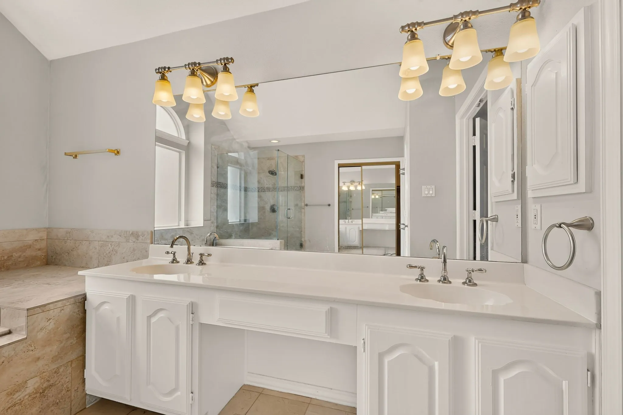 Bathroom featuring a dual vanity with white cabinetry, integrated sinks, and a large wall-mounted mirror