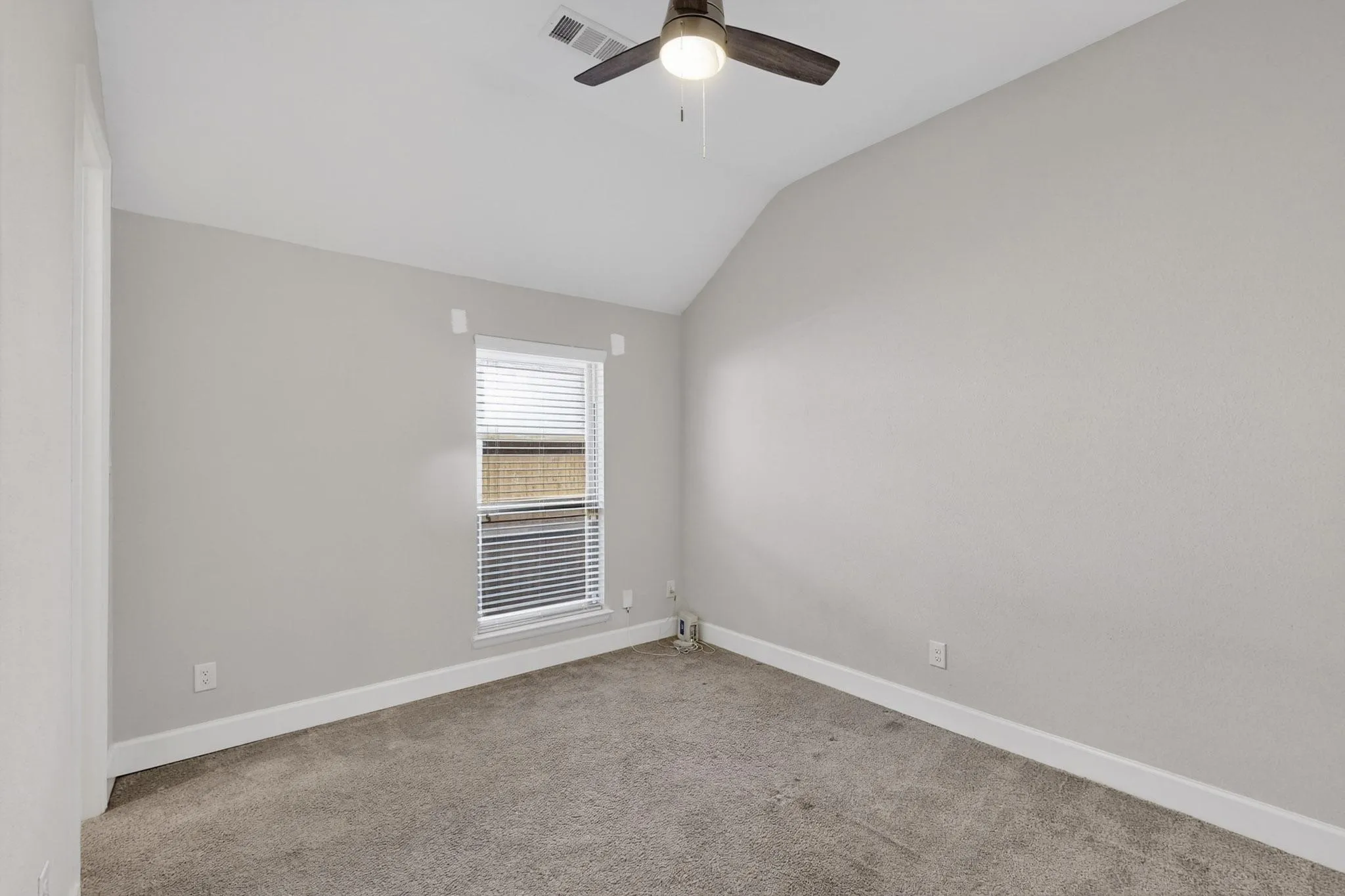 Carpeted empty room with lofted ceiling and baseboards
