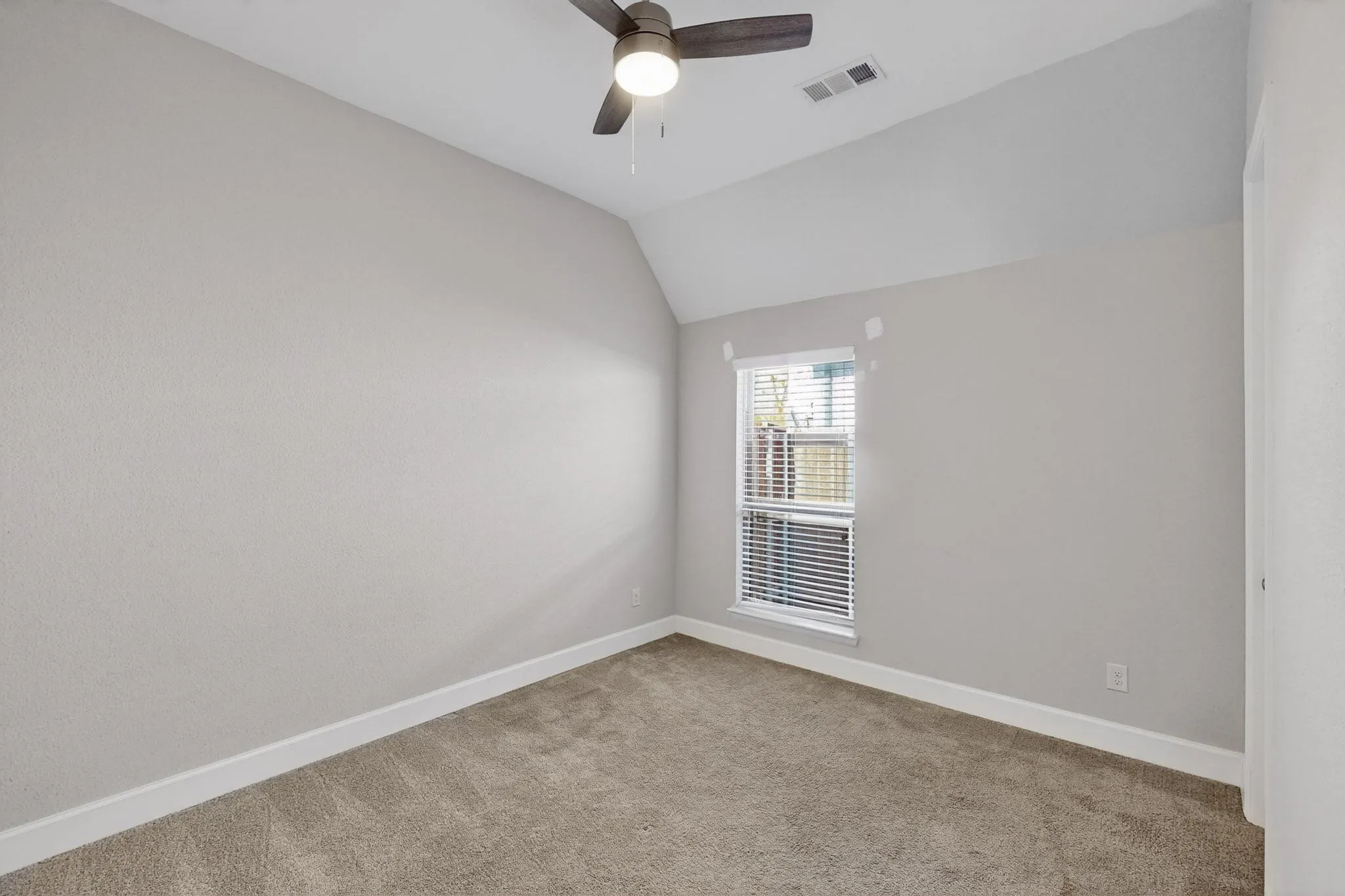 Empty room with lofted ceiling, light colored carpet, and a ceiling fan
