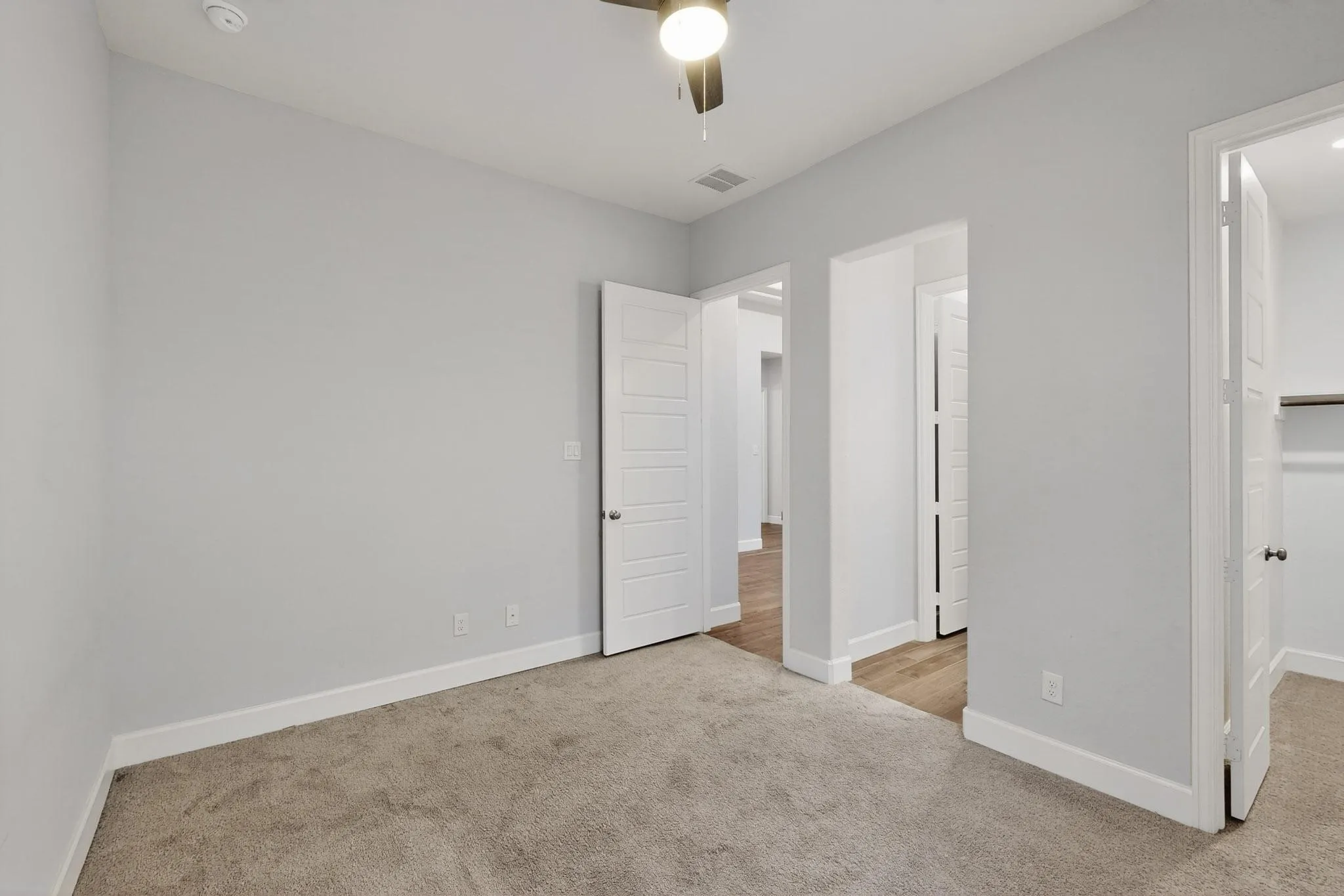 Unfurnished bedroom featuring light carpet, a walk in closet, and ceiling fan