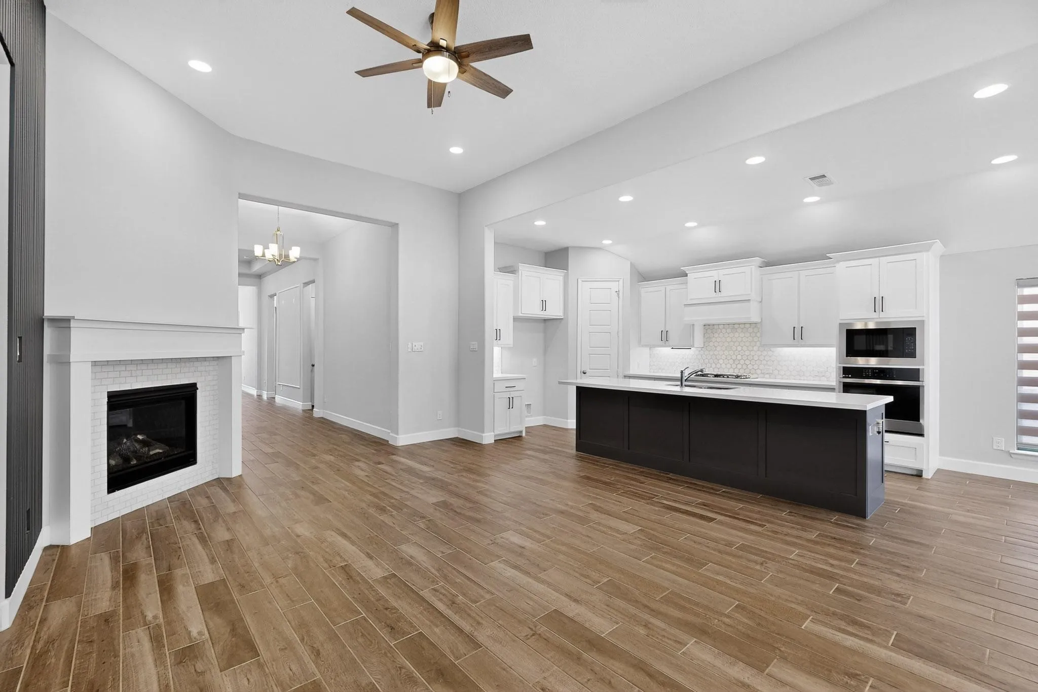 Kitchen featuring white cabinets, open floor plan, stainless steel oven, recessed lighting, and a glass covered fireplace