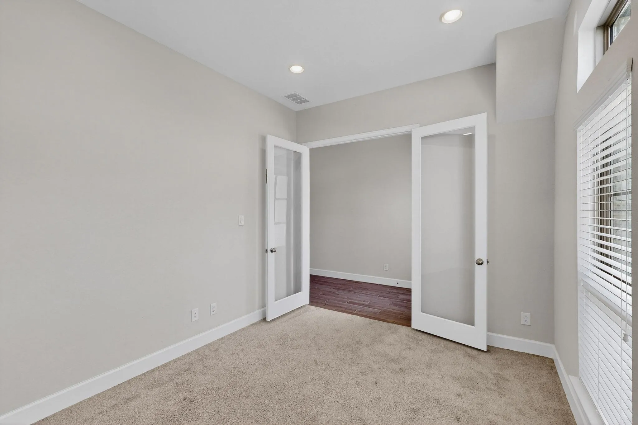 Unfurnished bedroom featuring french doors, light carpet, and recessed lighting