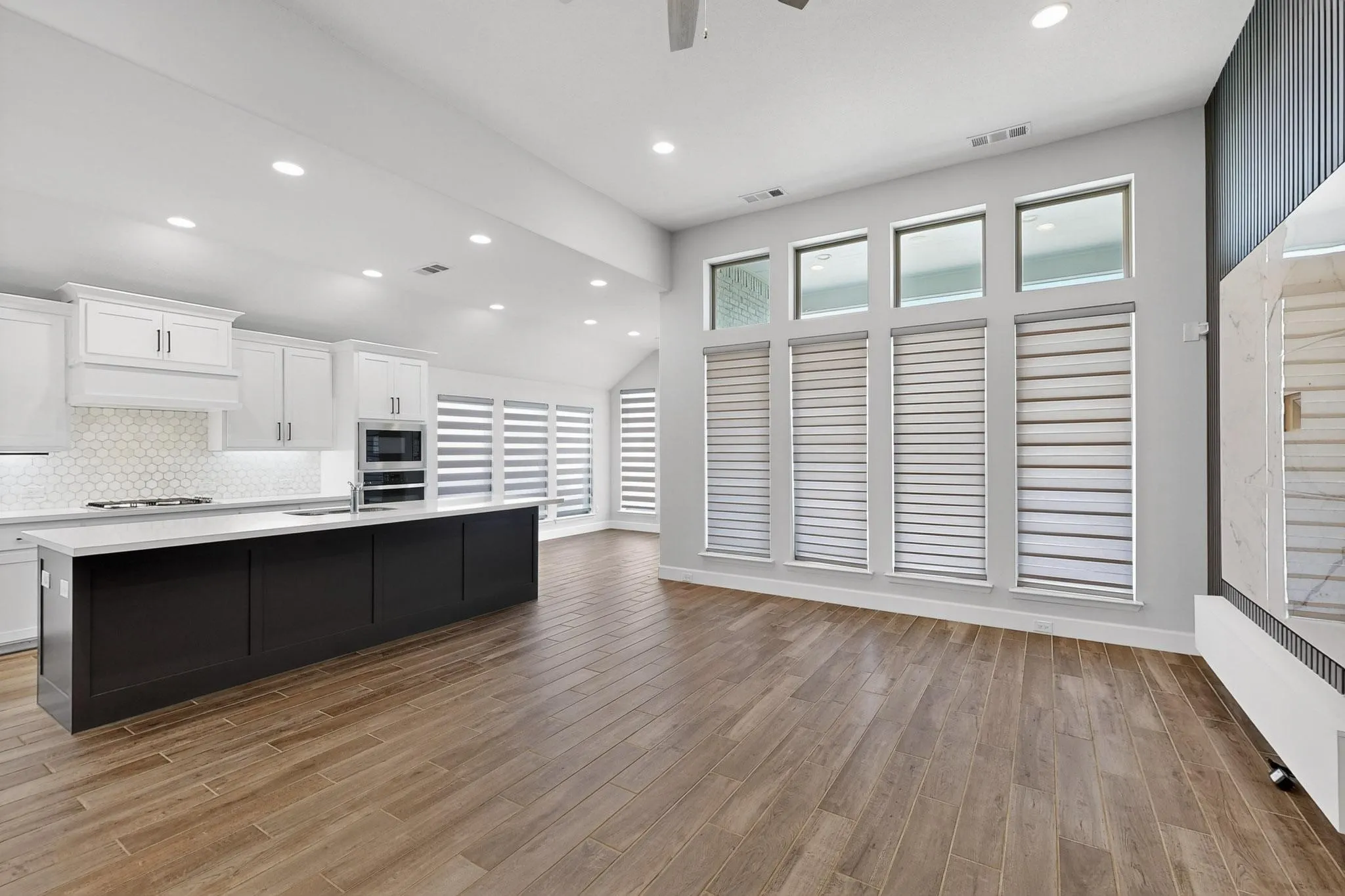 Kitchen with white cabinetry, recessed lighting, backsplash, a kitchen island with sink, and light wood-type flooring