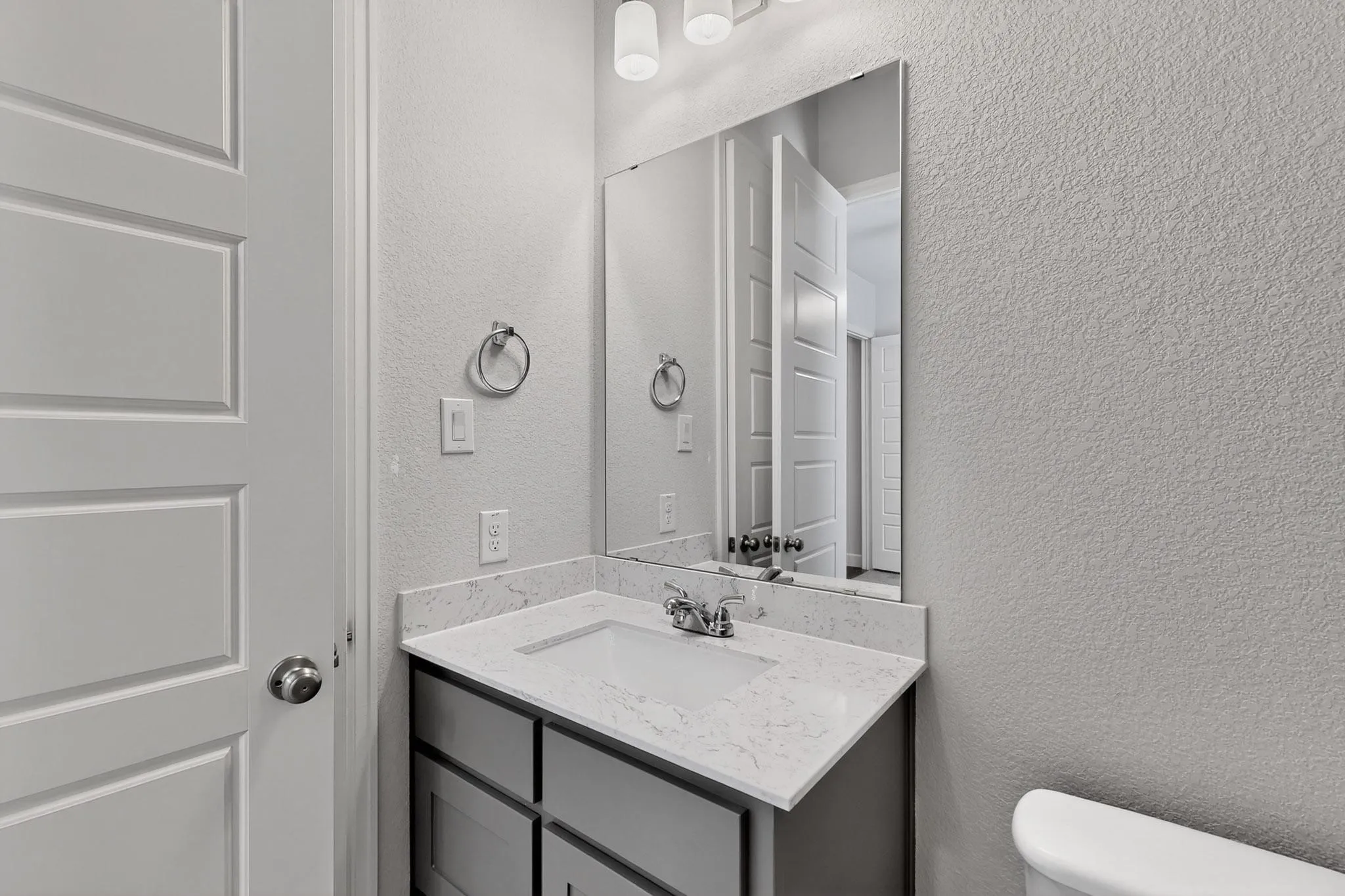 Half bathroom with a textured wall and vanity