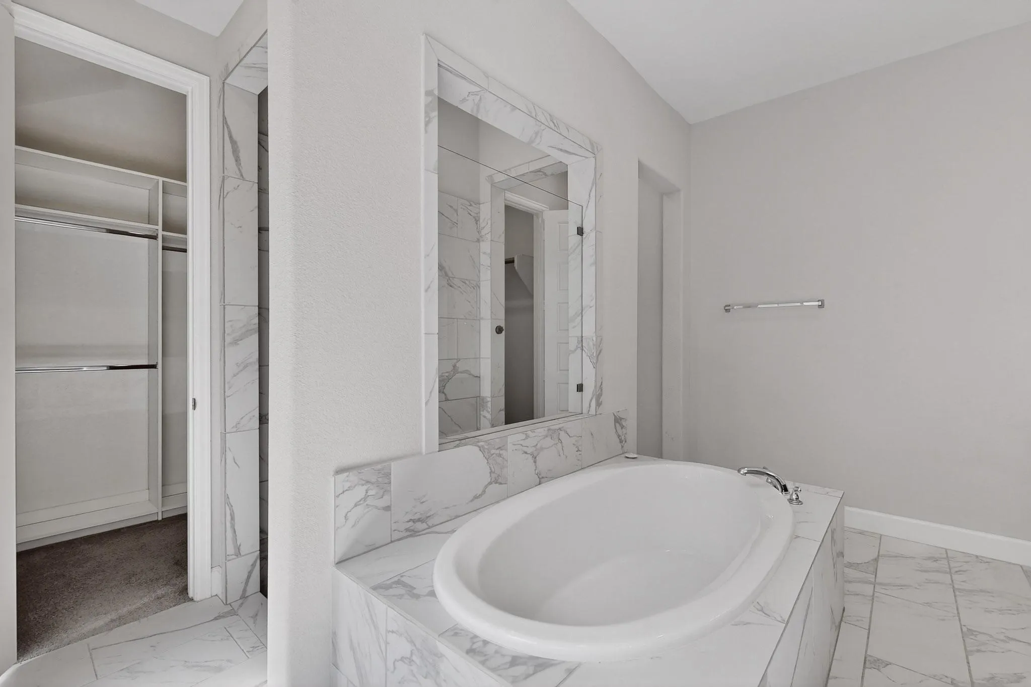Full bathroom featuring light marble finish floors, a bath, and a closet