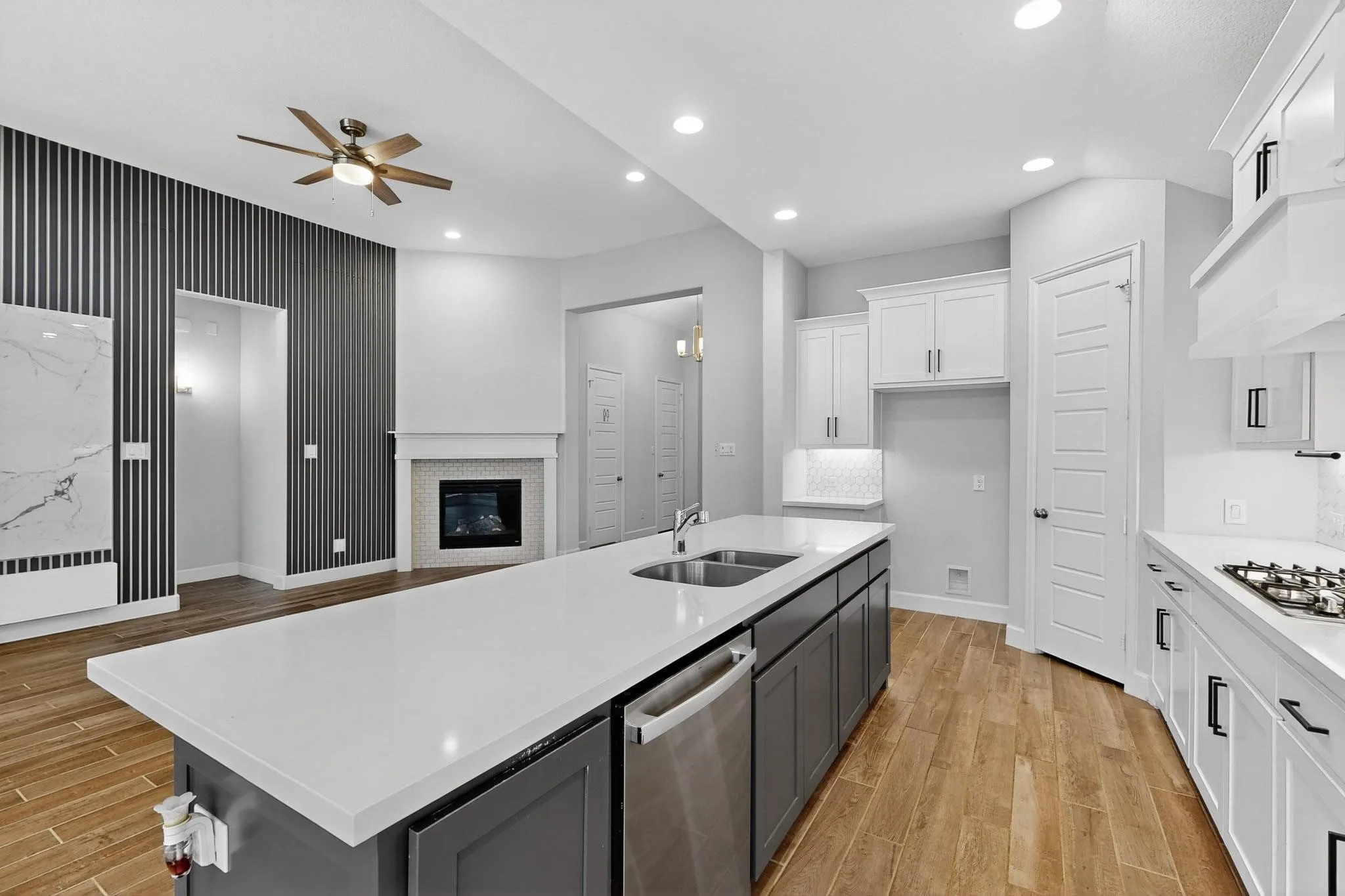 Kitchen featuring white cabinets, wood tiled floors, gray cabinets, stainless steel appliances, and a kitchen island with sink