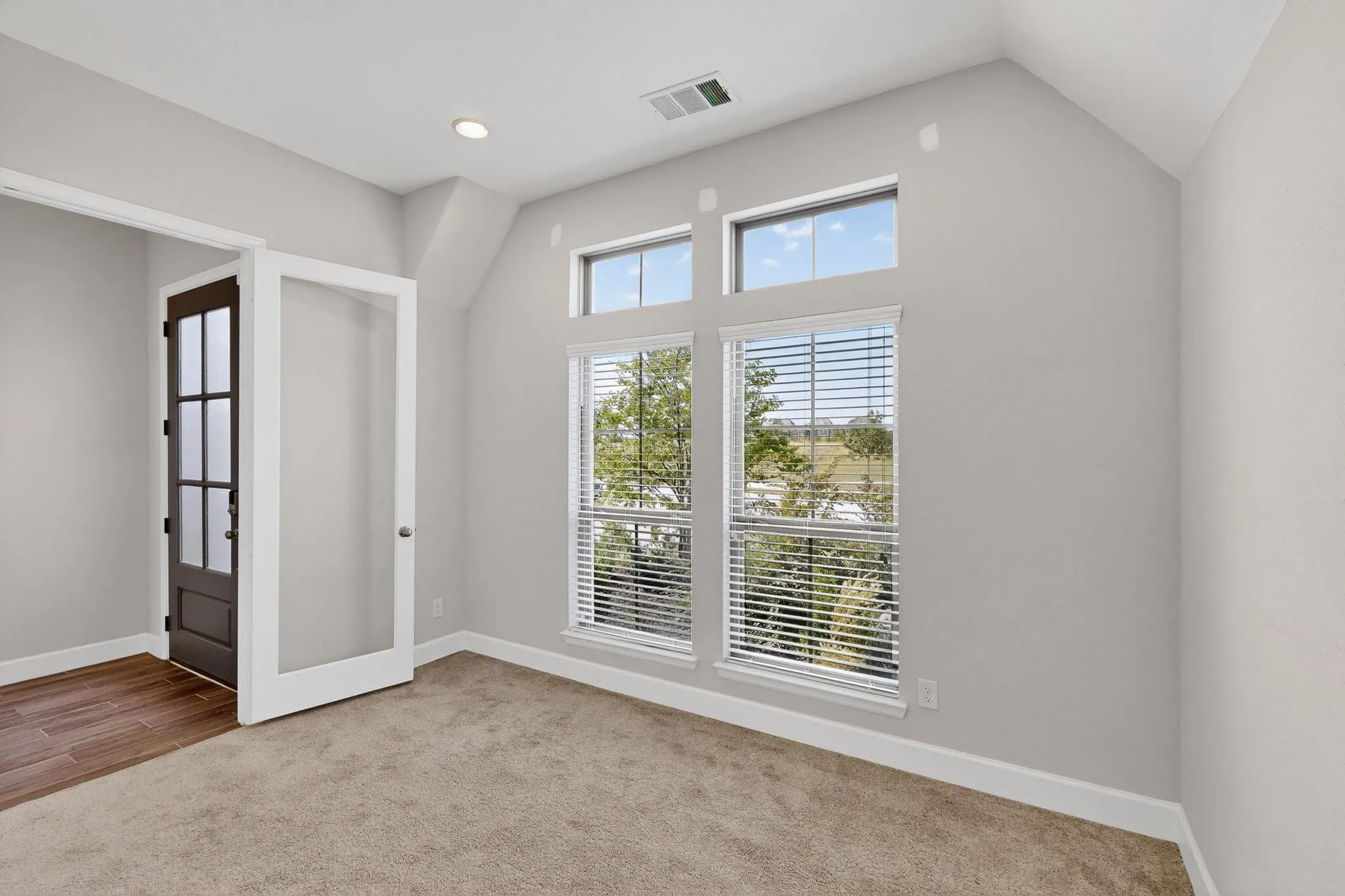 Unfurnished room with light carpet, french doors, and lofted ceiling