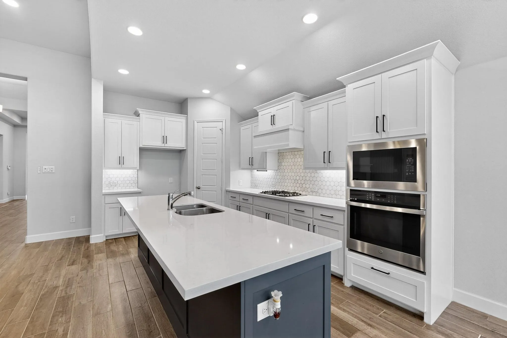 Kitchen featuring white cabinets, tasteful backsplash, appliances with stainless steel finishes, recessed lighting, and a kitchen island with sink