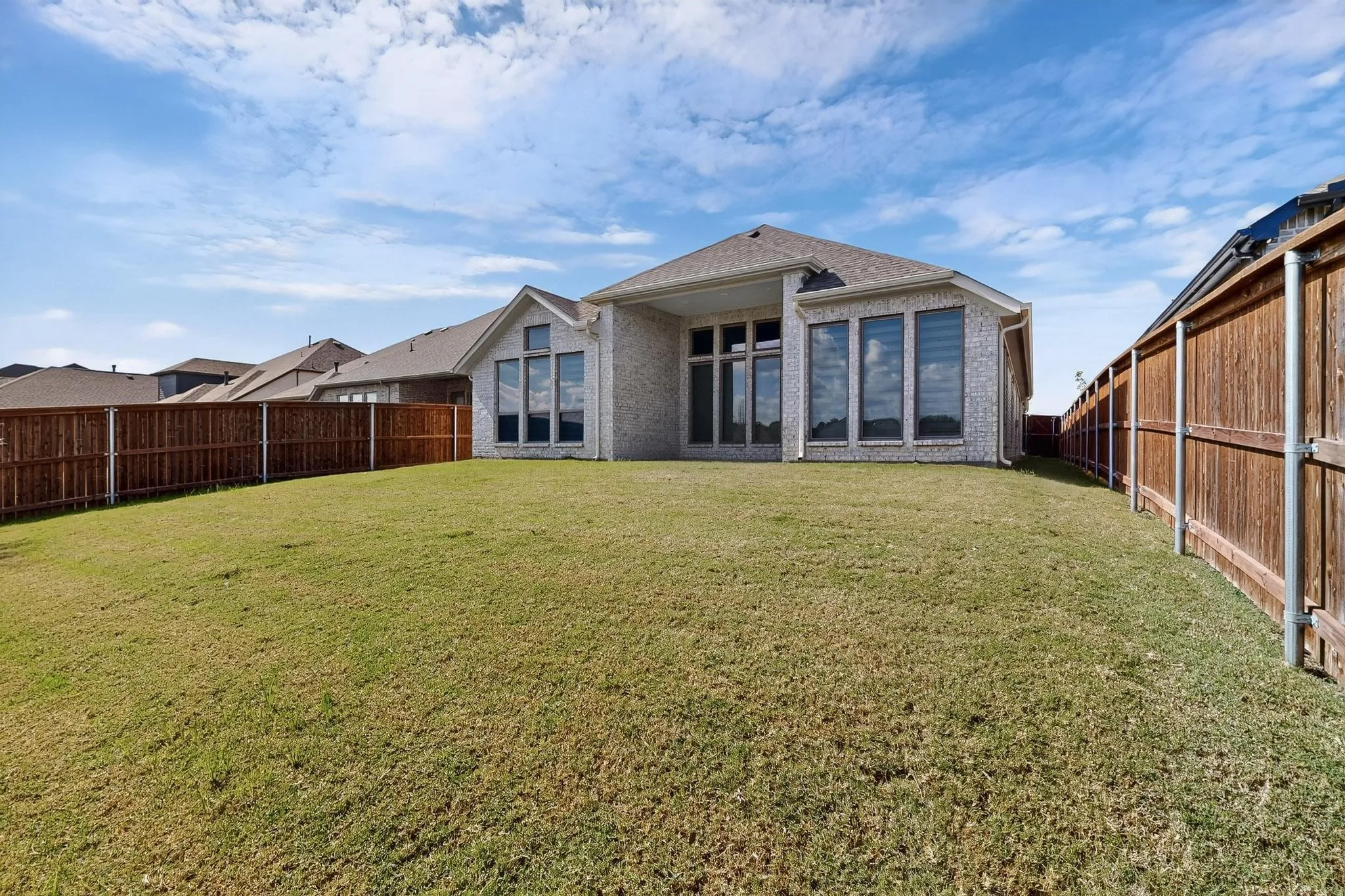 Back of house with a fenced backyard, a patio area, and brick siding