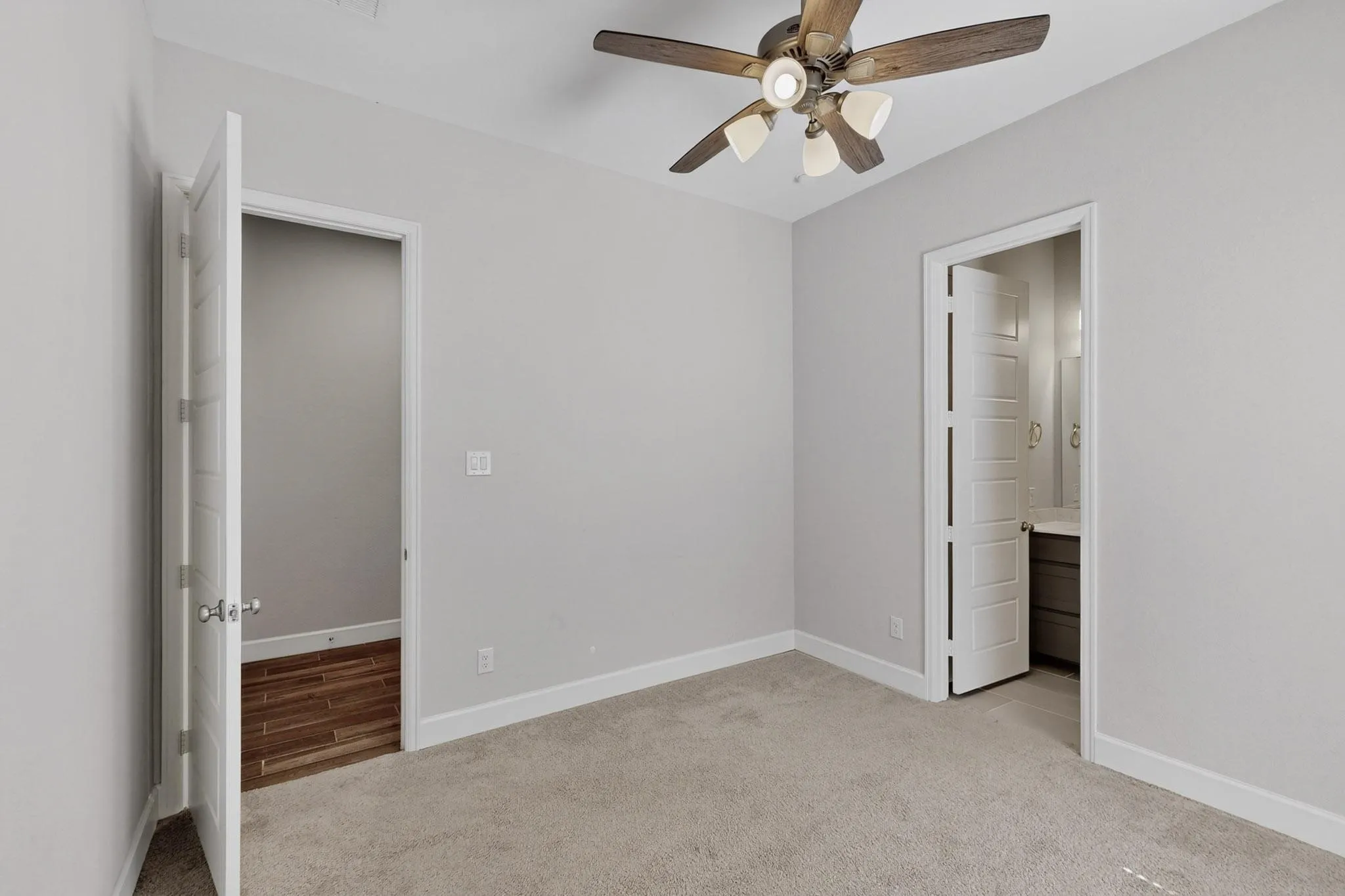Unfurnished bedroom featuring light carpet, a ceiling fan, and ensuite bathroom