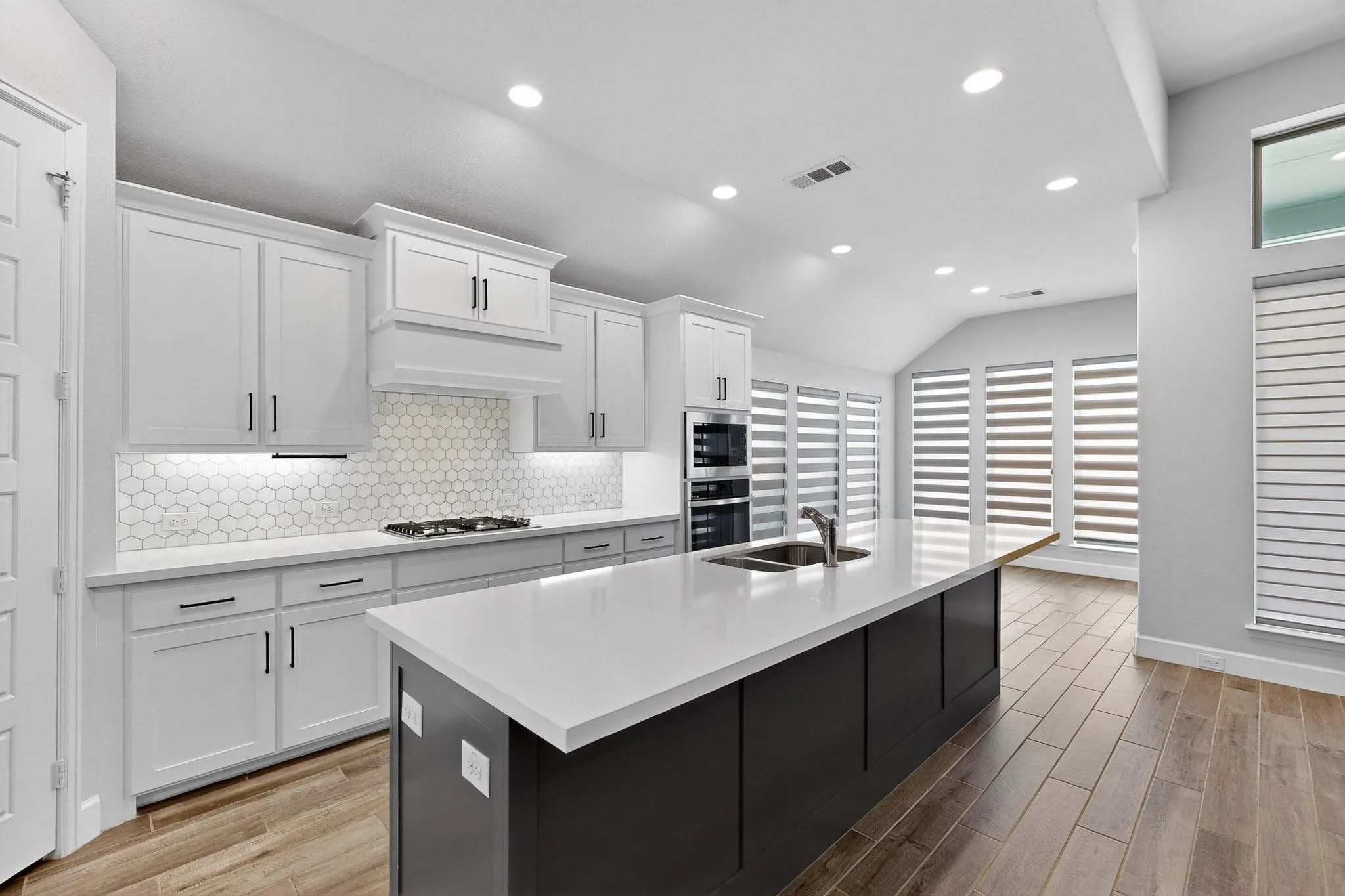 Kitchen featuring backsplash, recessed lighting, white cabinets, light wood finished floors, and lofted ceiling
