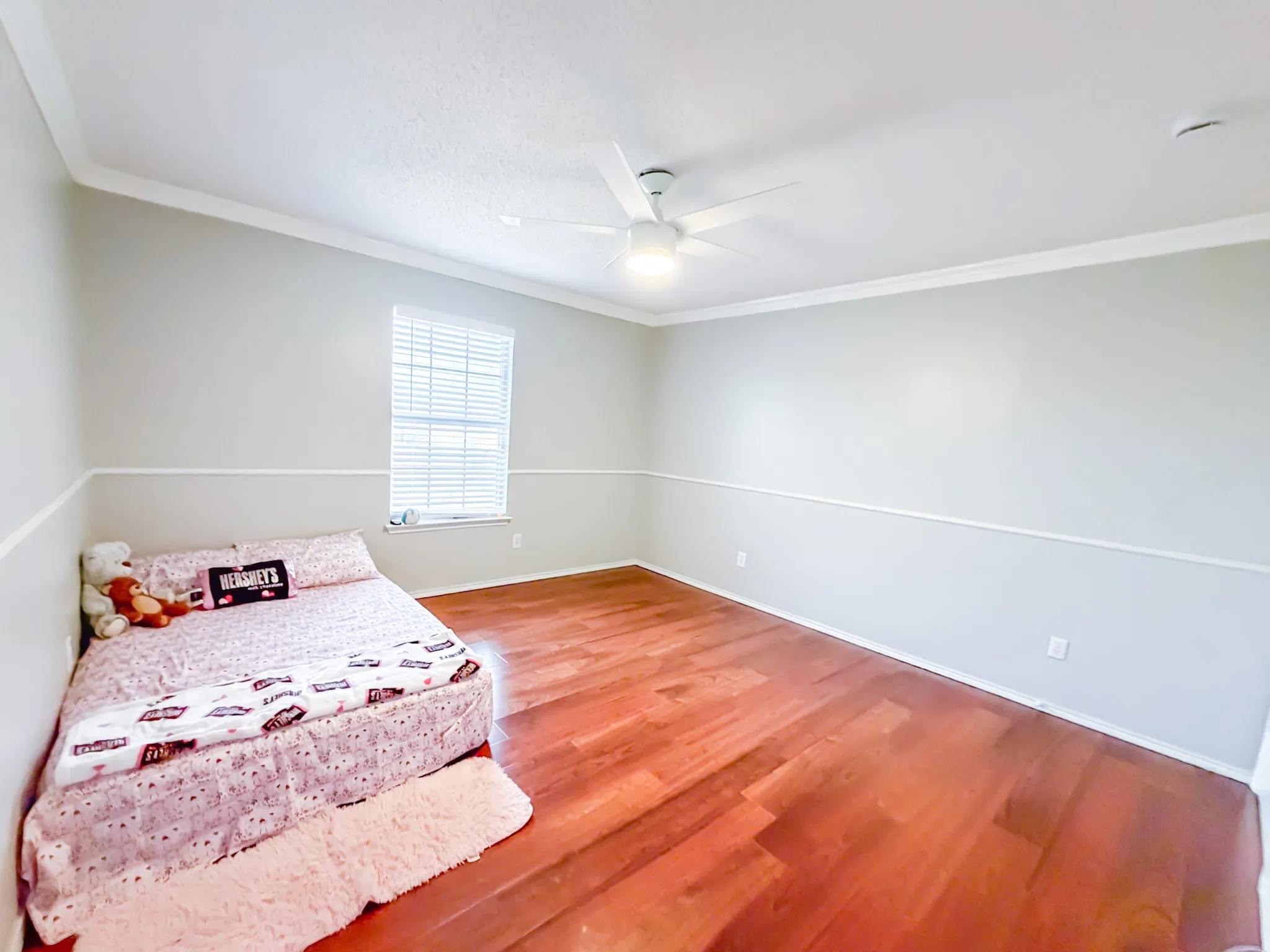 Room featuring rich wood-finish flooring, a ceiling fan with integrated lighting, and a window with horizontal blinds