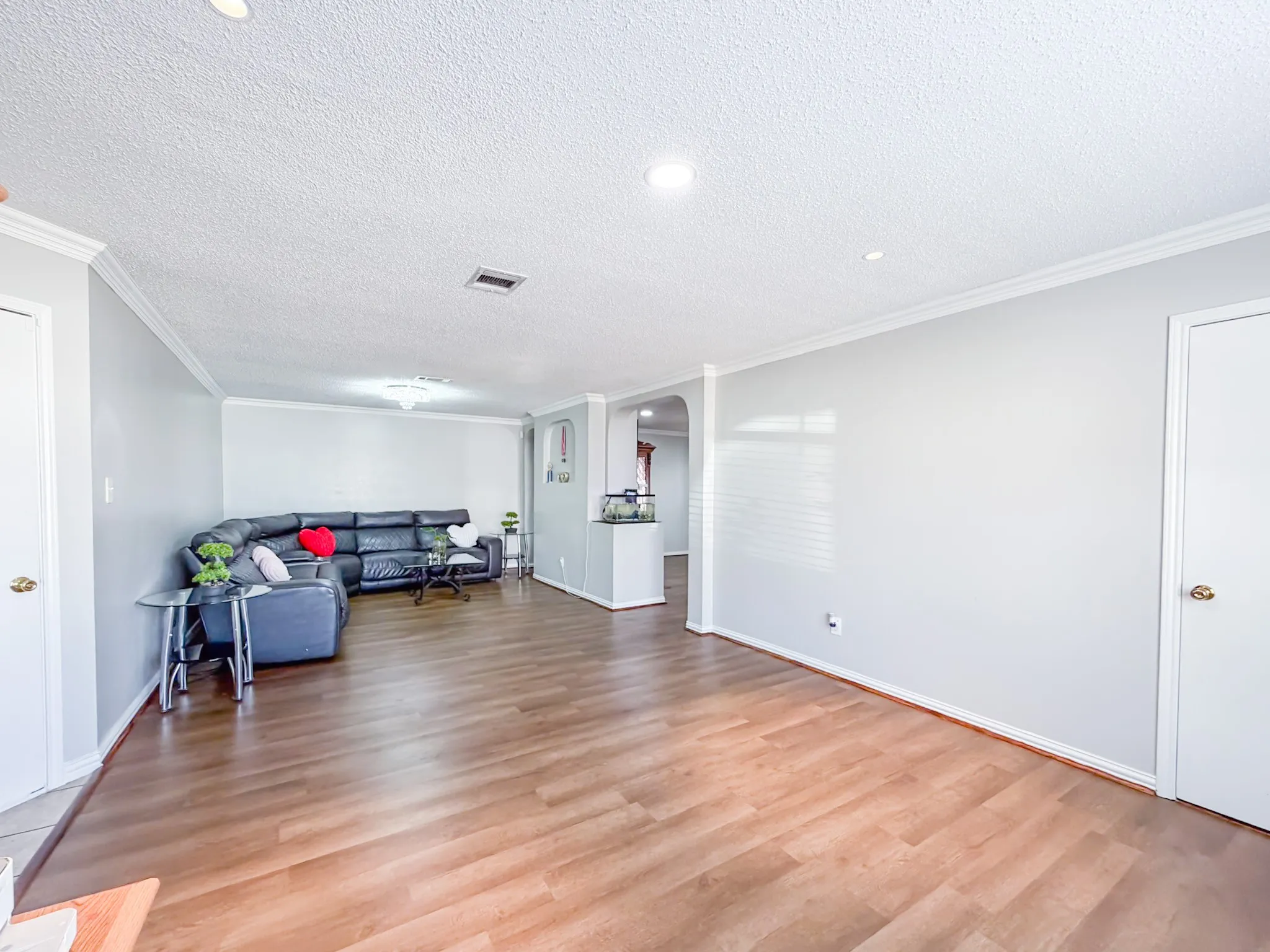 Spacious interior featuring wood-finish flooring, light grey painted walls, white crown molding, and recessed lighting
