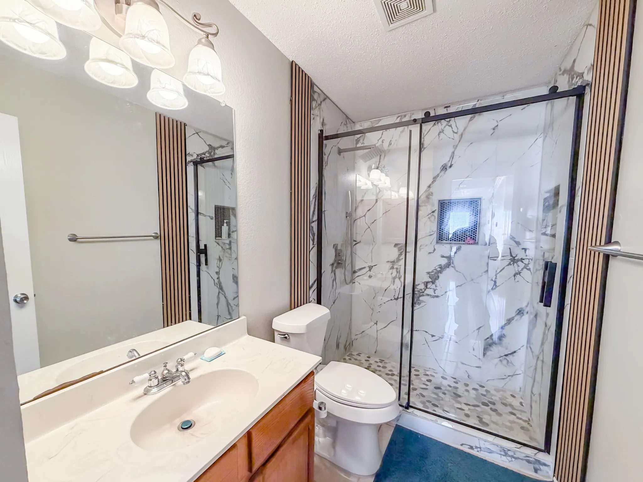 Bathroom featuring a wood-finish vanity with a light-toned countertop, a rectangular undermount sink, and a large wall-mounted mirror