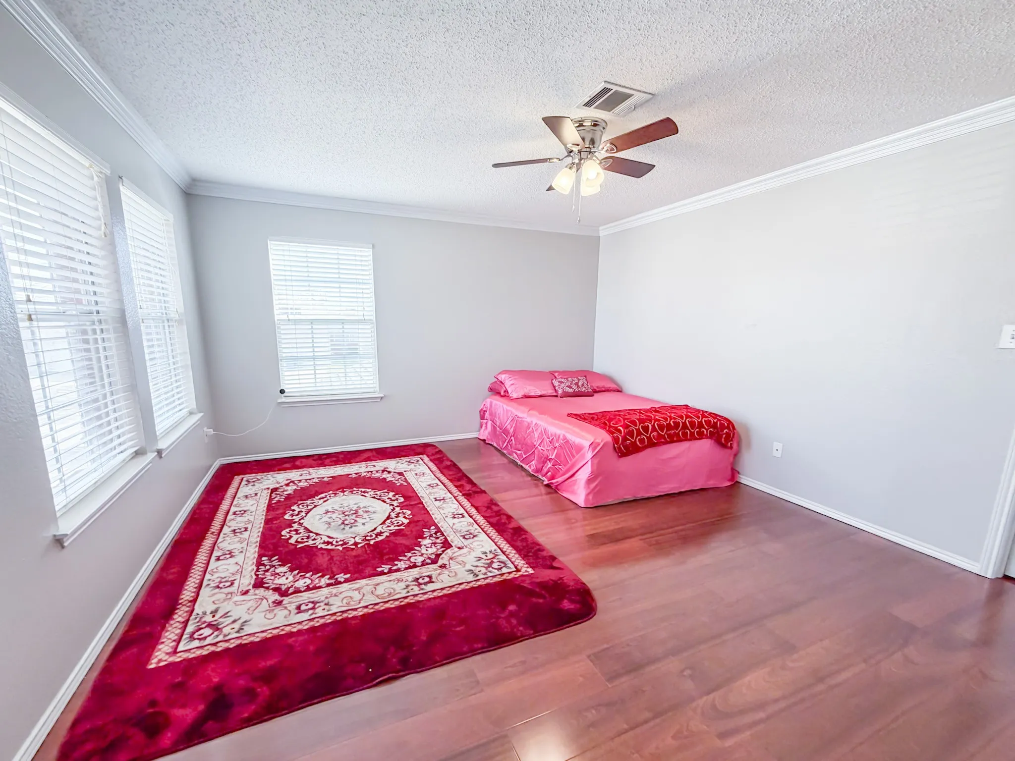 Spacious room featuring rich wood-finish flooring and light gray walls