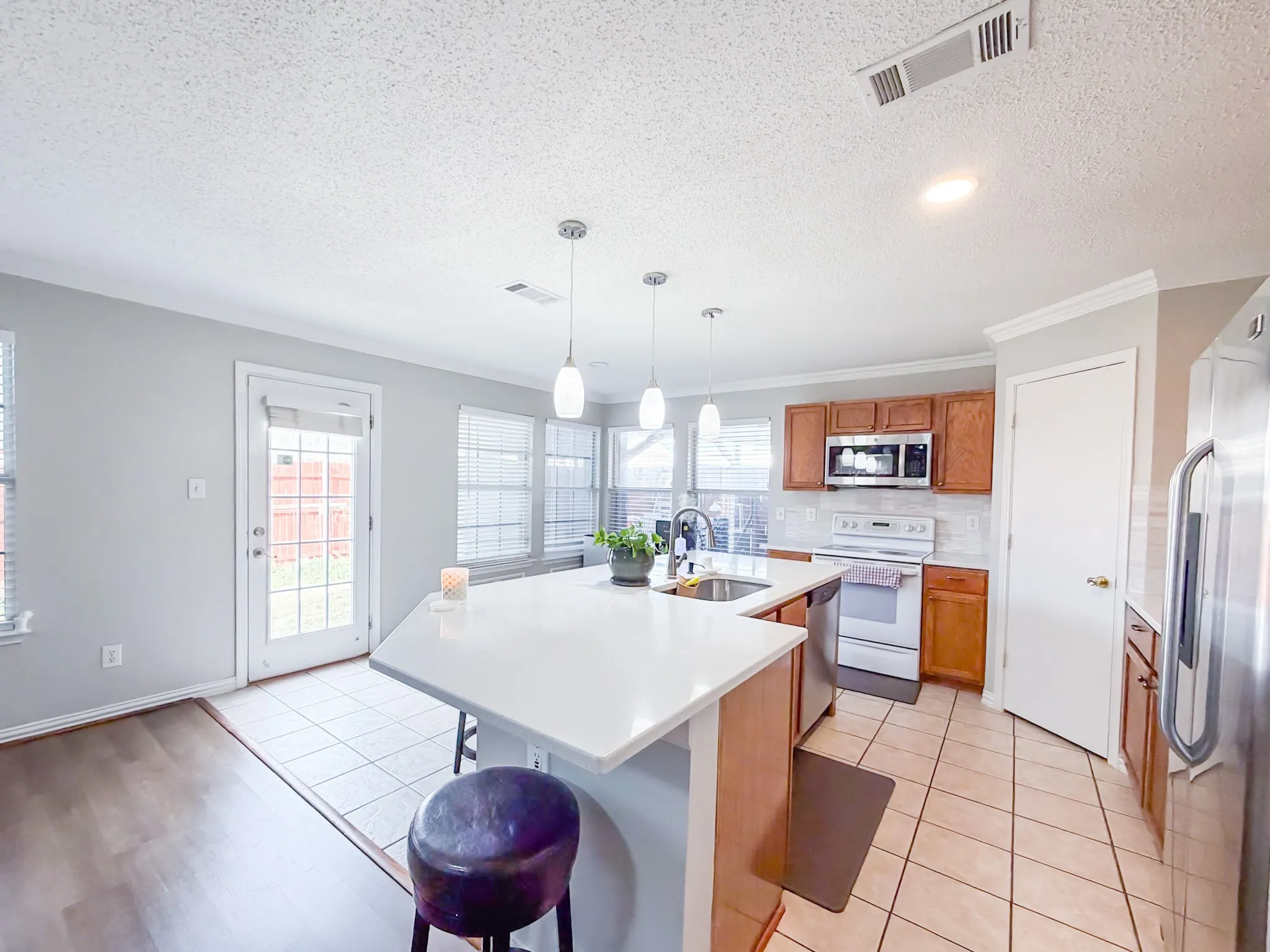 Kitchen featuring a central island with white countertop, pendant lighting, and stainless steel appliances