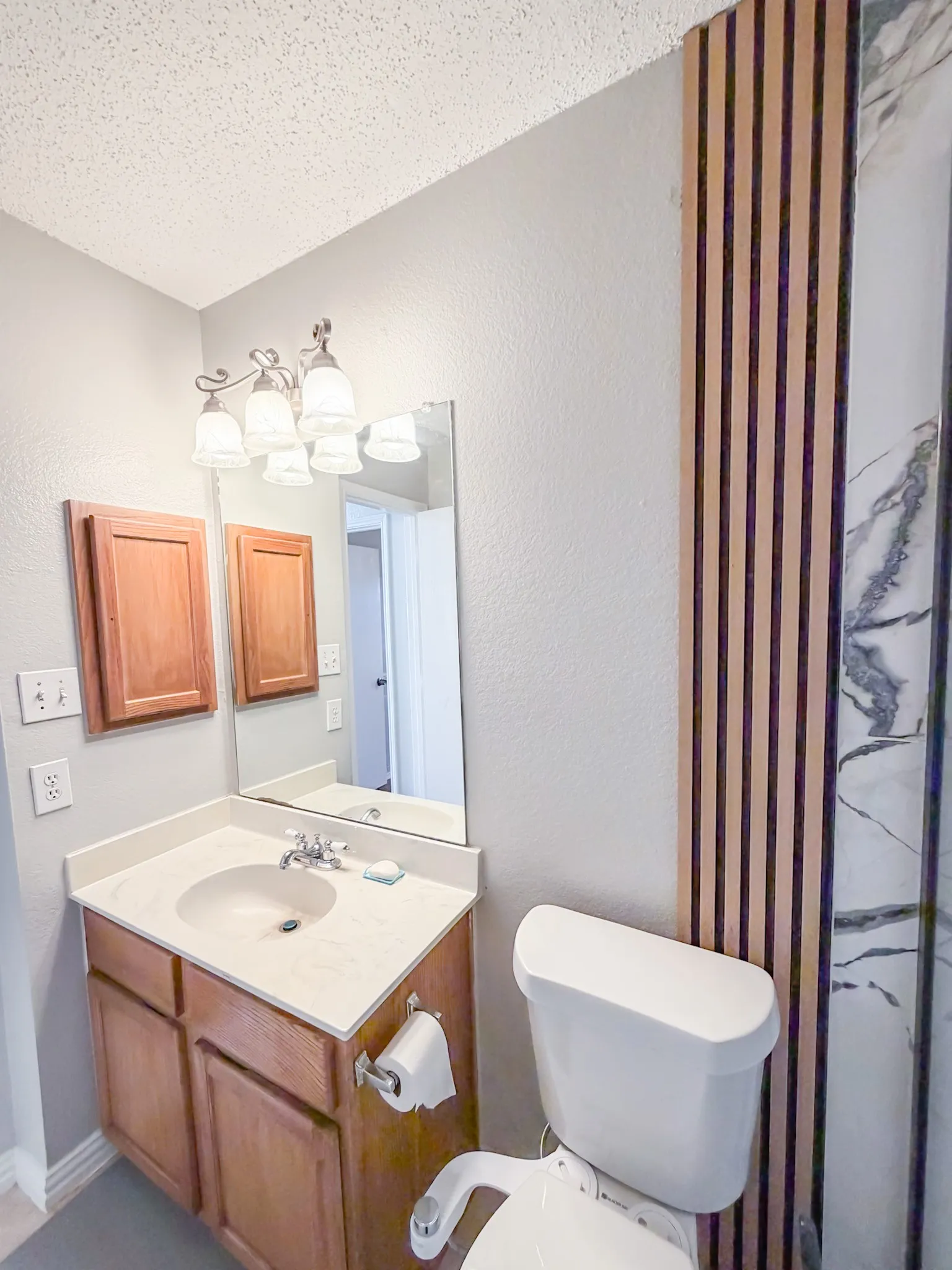 Bathroom featuring a single vanity with a laminate countertop, built-in medicine cabinets, and a contemporary light fixture