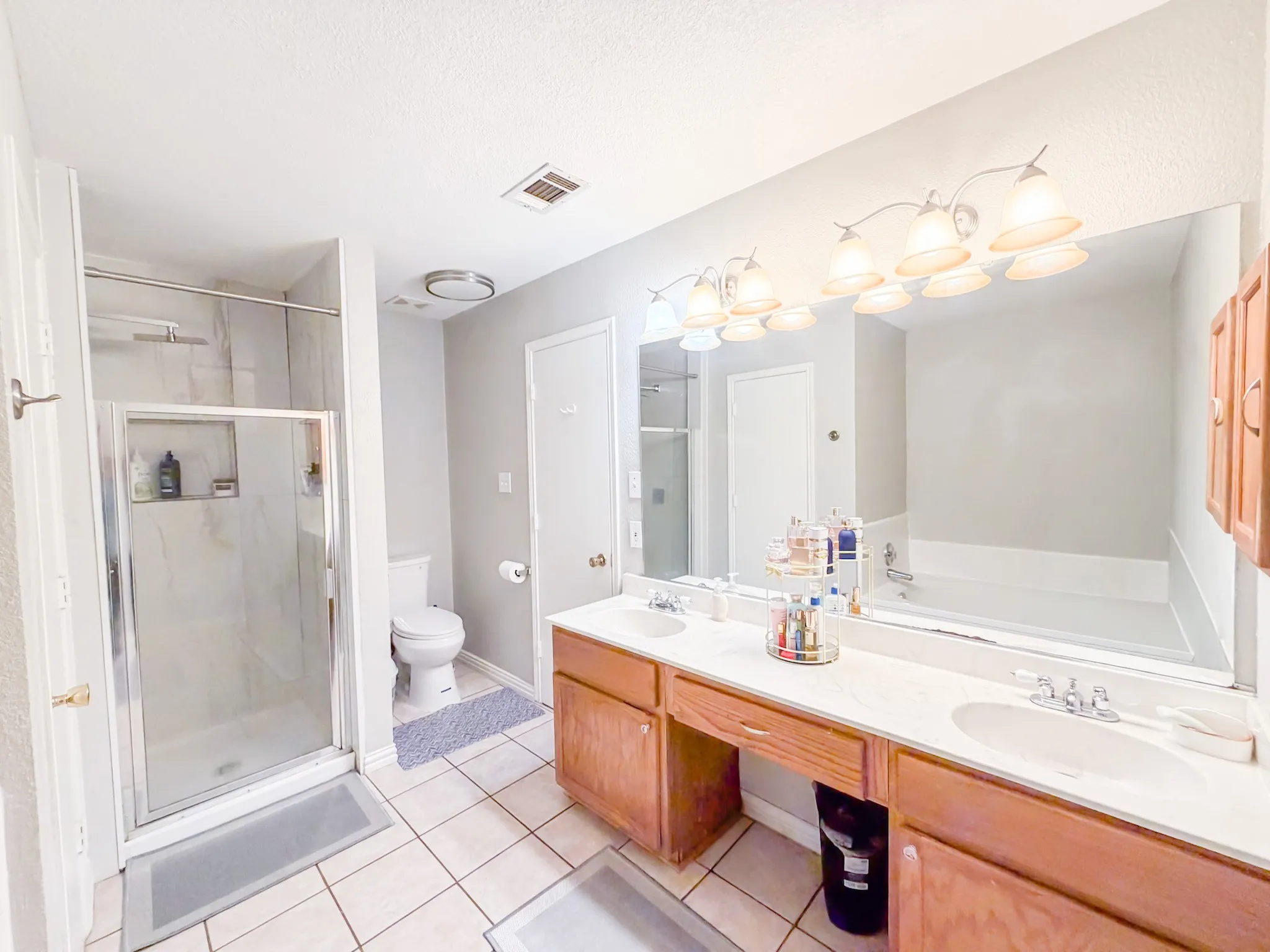 Bathroom featuring a double vanity with light wood cabinetry, a built-in makeup area, and individual sinks