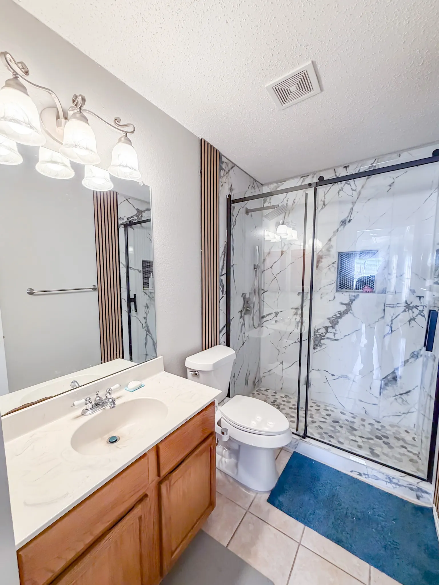 Modern bathroom with a spacious walk-in shower featuring a sliding glass door and stone pebble flooring