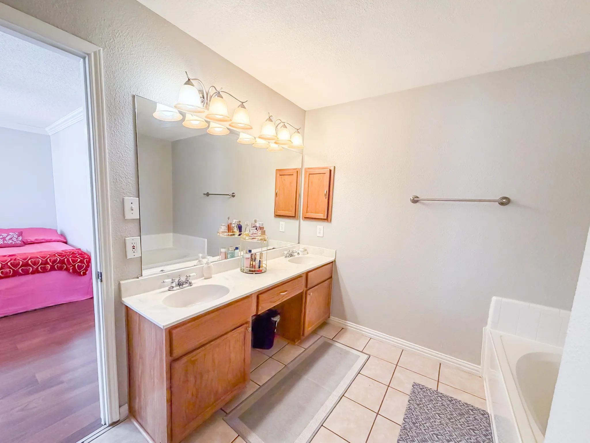 Bathroom featuring a dual vanity with light-colored countertops, wood-finish cabinetry, and overhead lighting