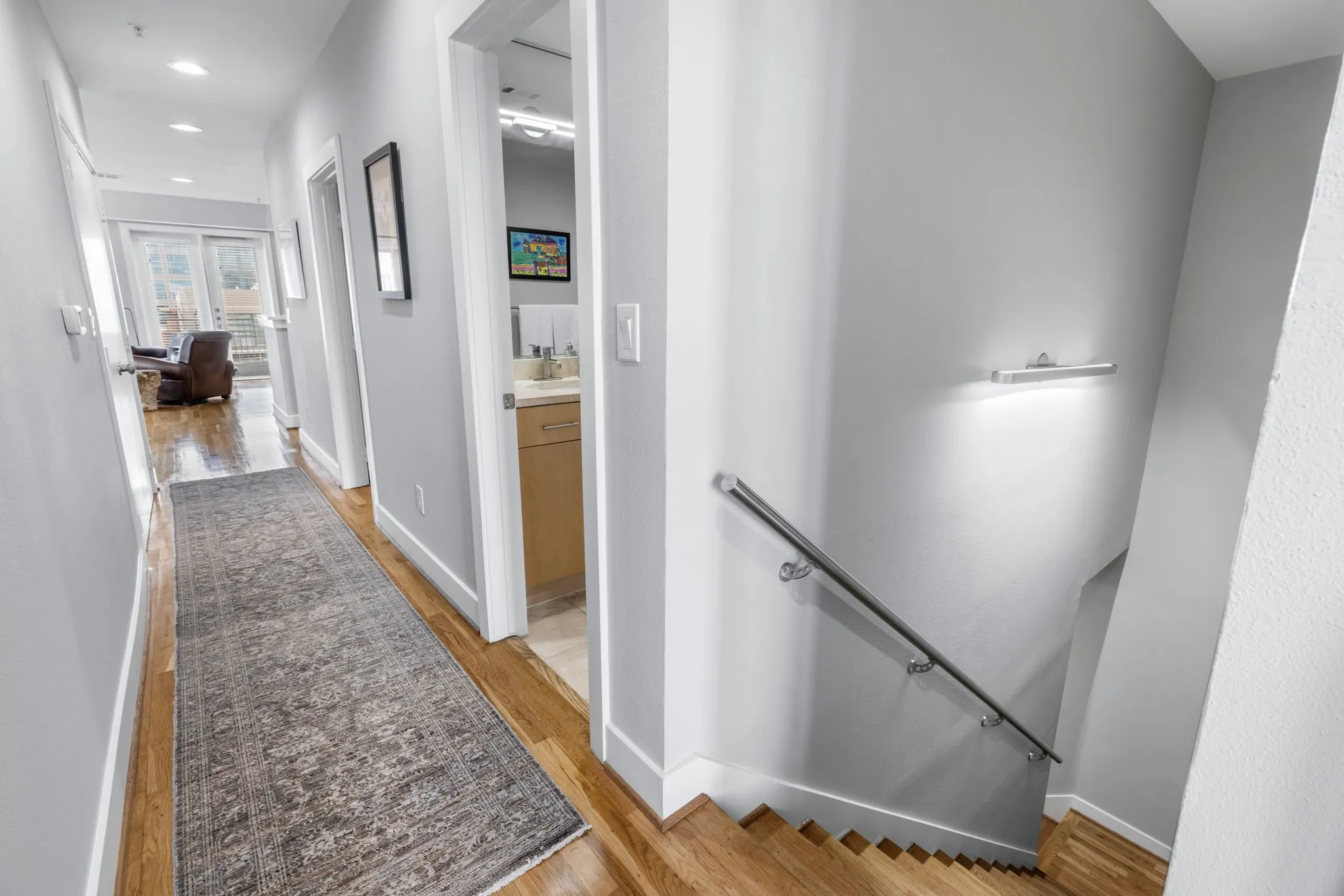 The stairs lead up to a hallway at the center of the unit. Secondary bathroom is conveniently located for guests. Living area is to the right, bedrooms to the left.