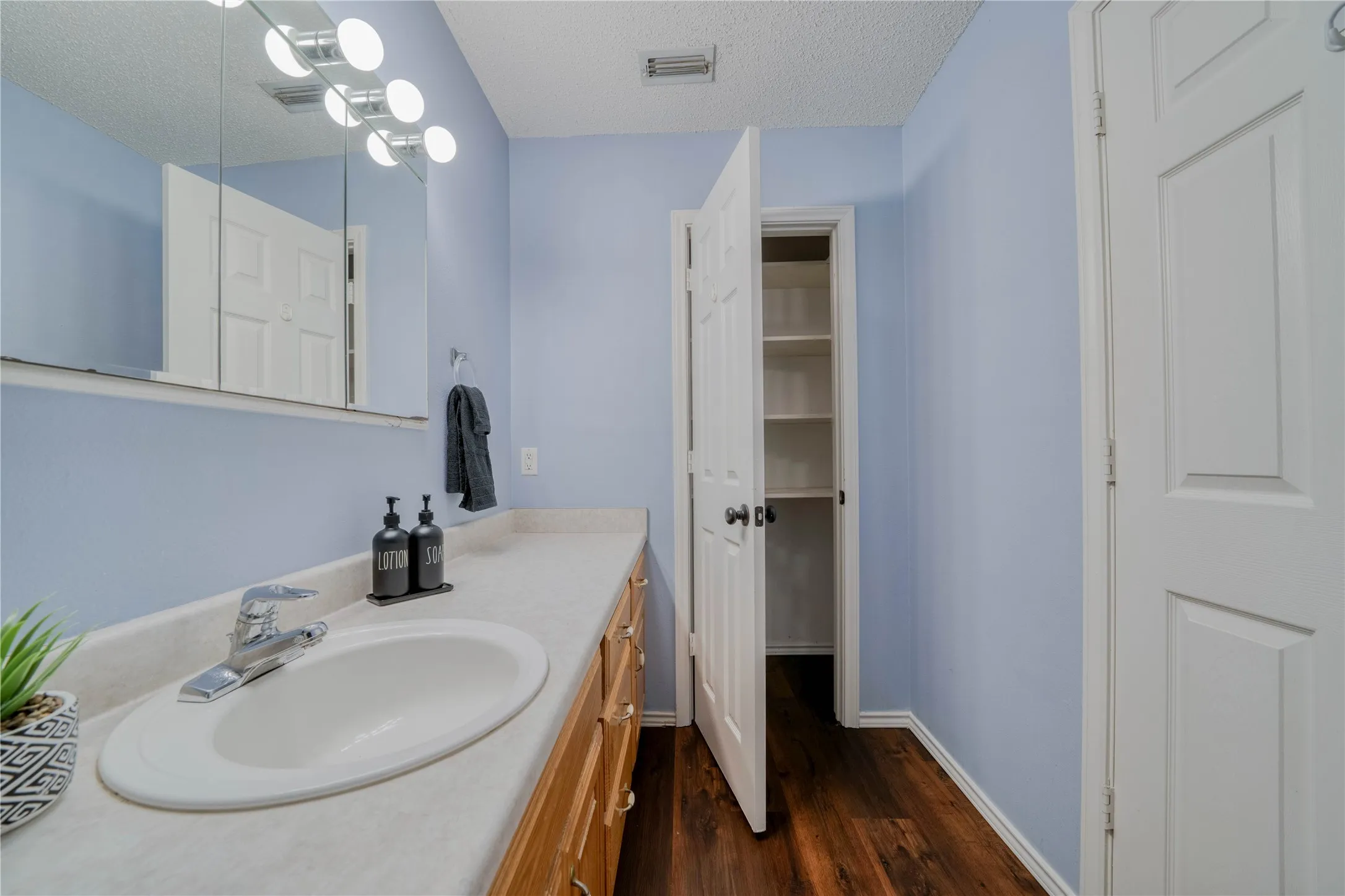 Bathroom vanity featuring an integrated sink, laminate countertop, and wood-finish cabinetry