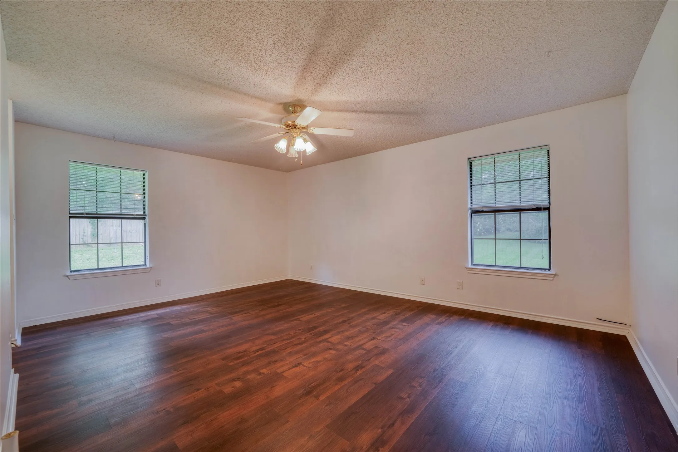 Spacious interior with dark wood-finish flooring, white walls, and a textured ceiling