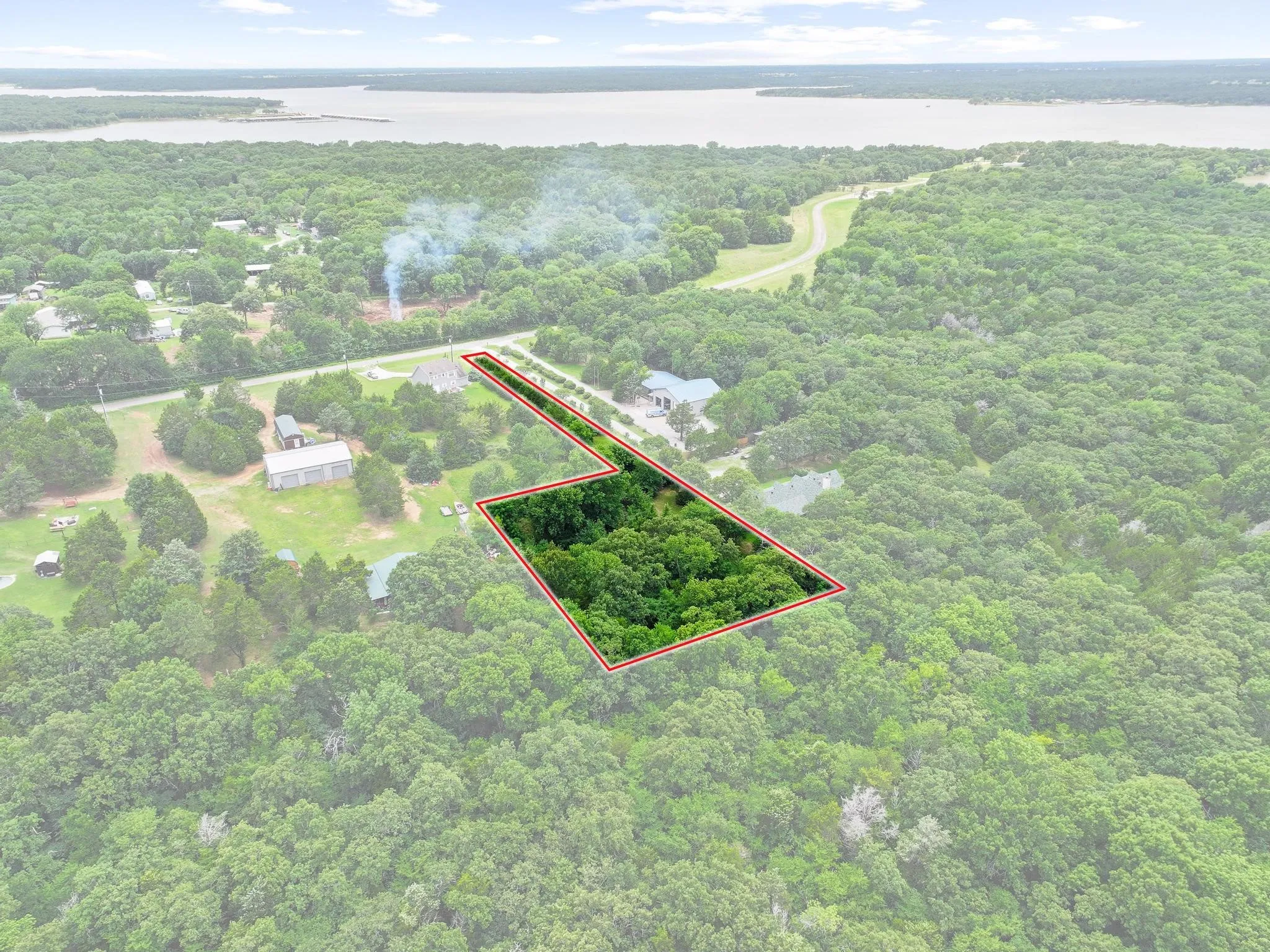Expansive wooded parcel featuring mature trees, a defined property boundary, and proximity to a large body of water
