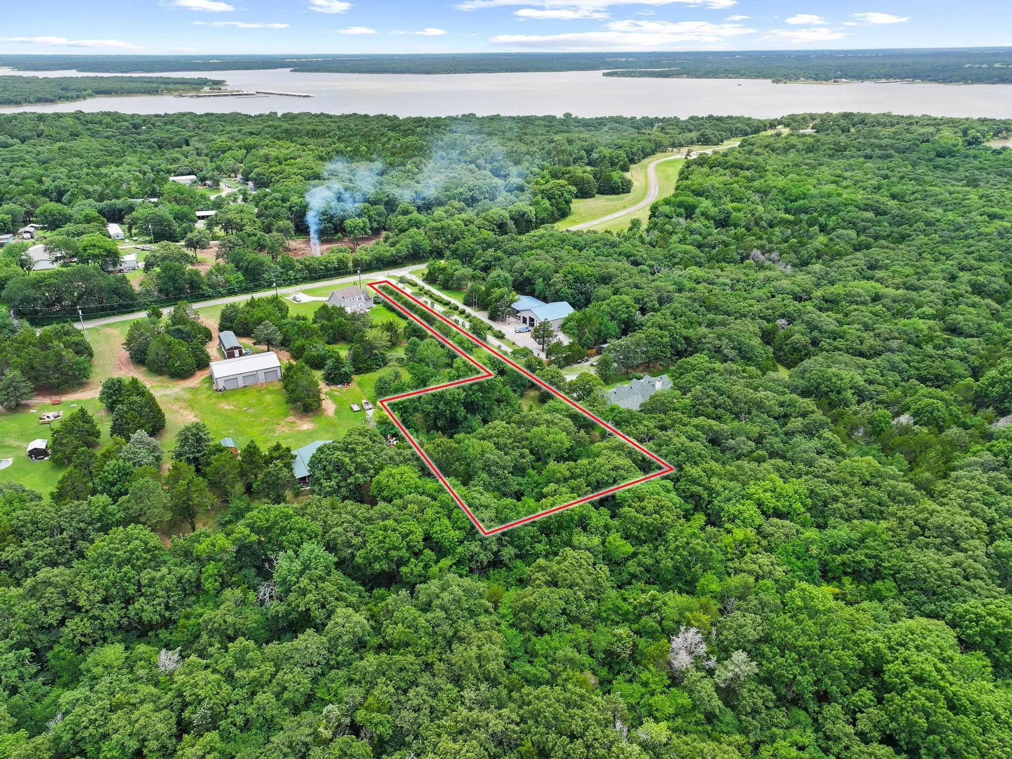 Aerial perspective showcasing a large, heavily wooded parcel with a clear boundary outline, featuring significant tree coverage and proximity to a large body of water