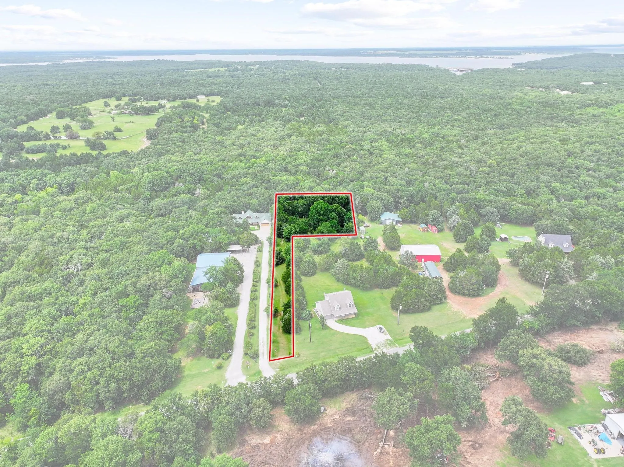 Expansive wooded parcel outlined in red, featuring a private drive and mature trees