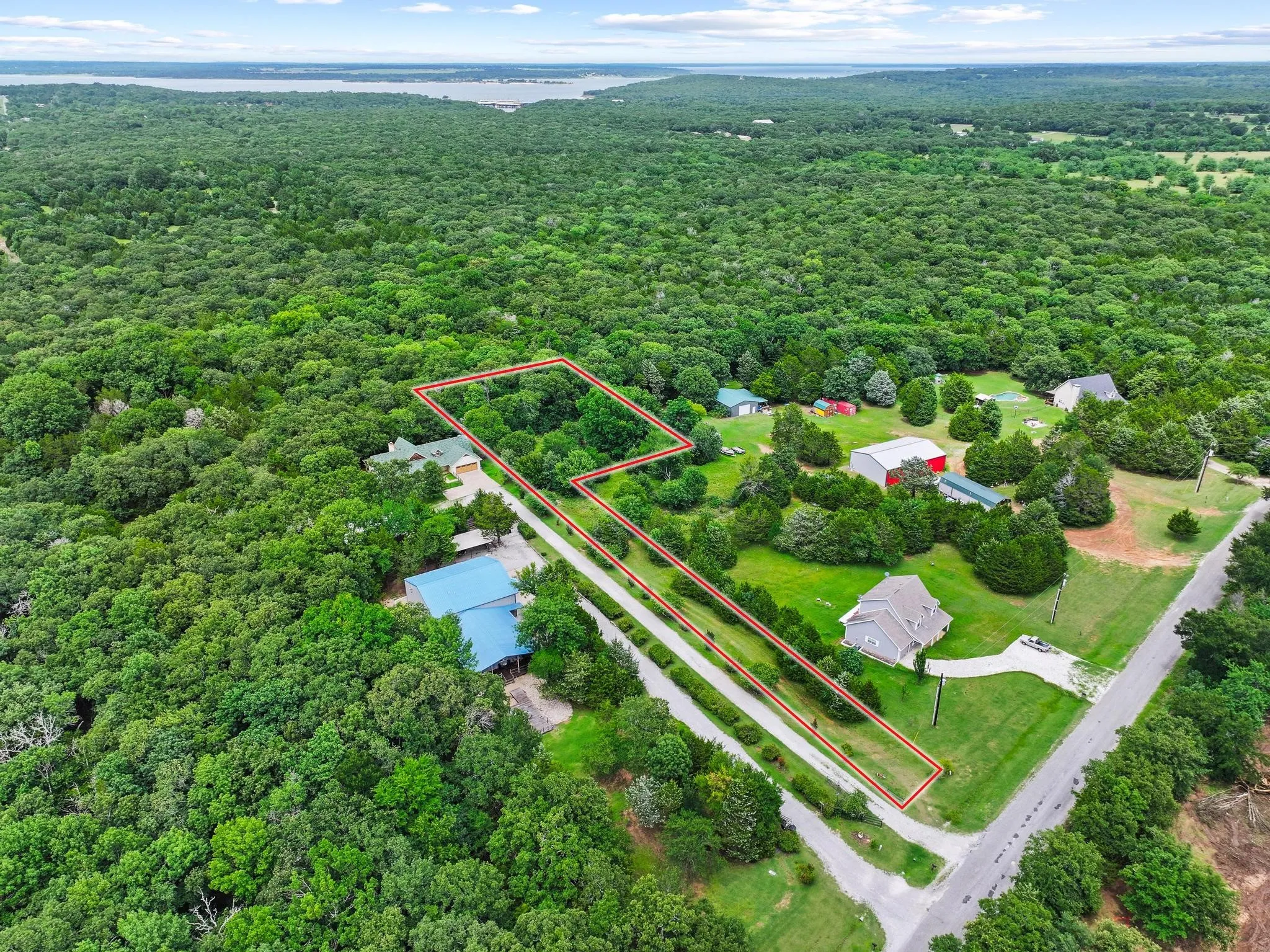 Aerial view of a sprawling property featuring extensive tree coverage, a defined parcel outline, and a visible roadway