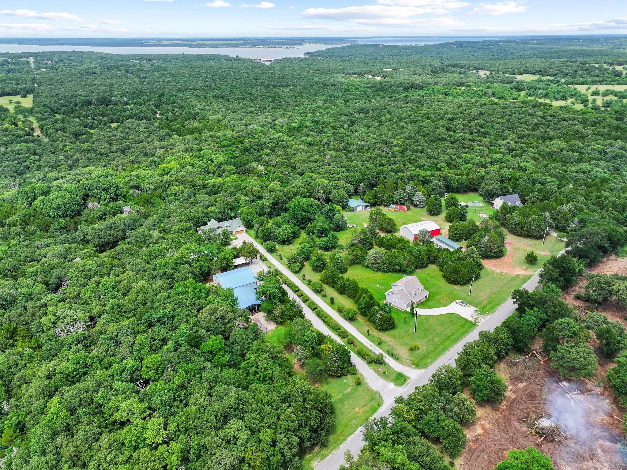 Expansive property featuring dense tree coverage, multiple structures, and a long private driveway