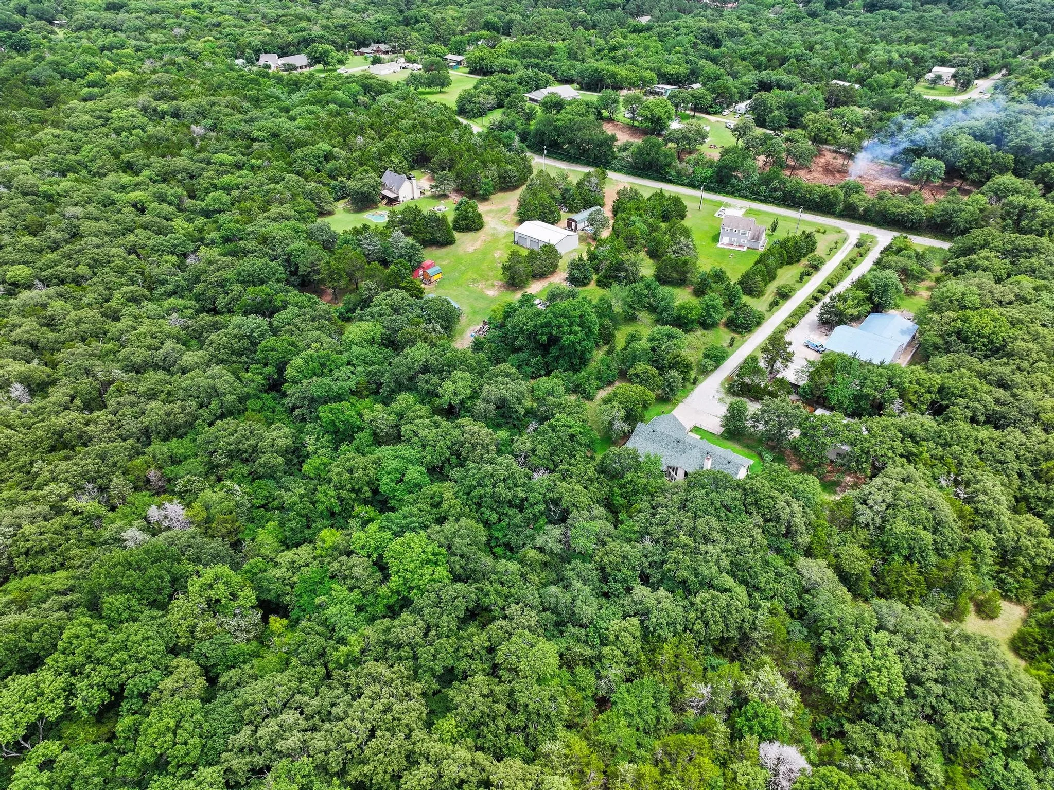 Expansive wooded acreage featuring multiple residential structures and paved roadways