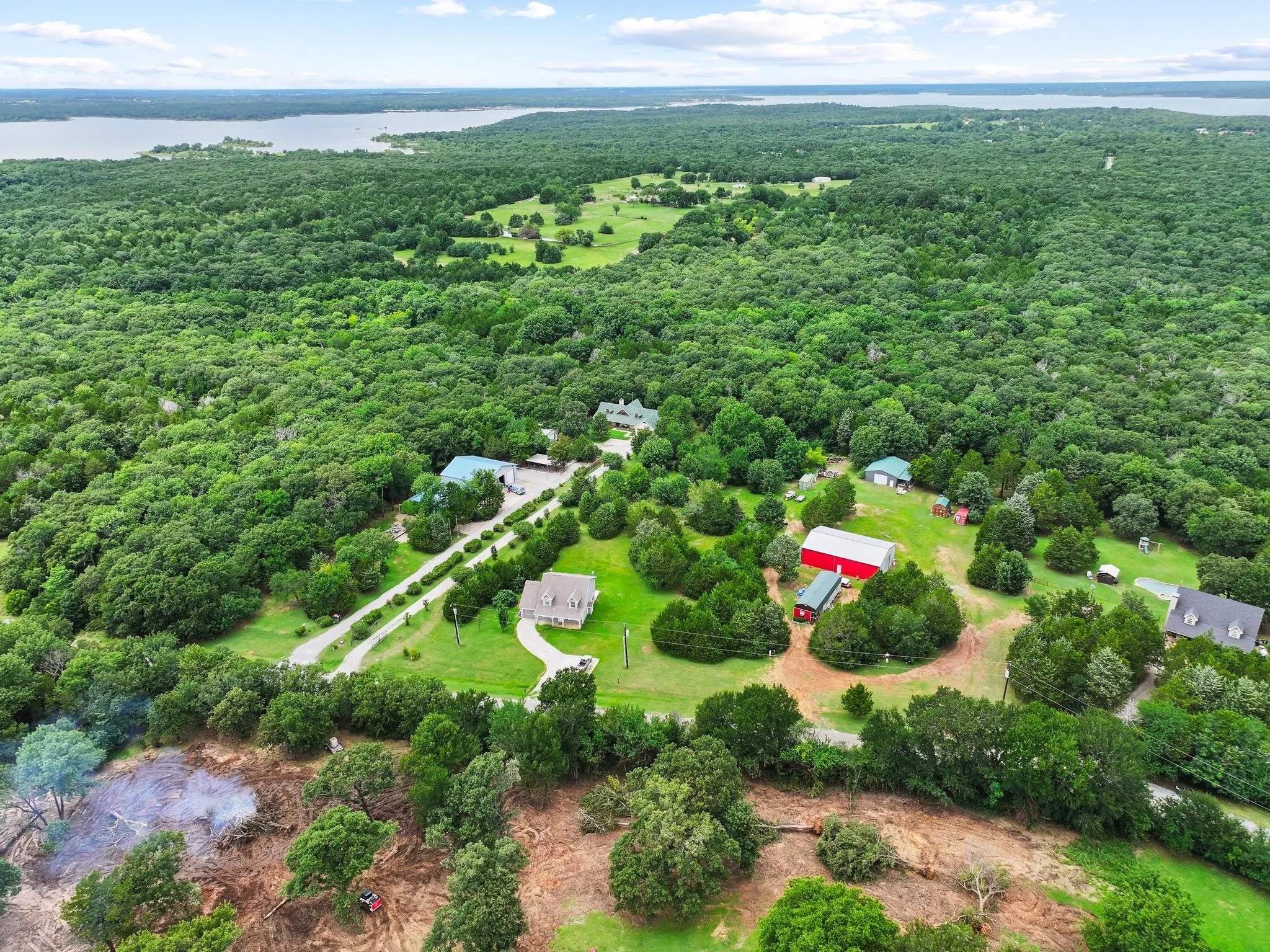 Expansive rural property featuring a large body of water in the background, surrounded by extensive natural tree cover
