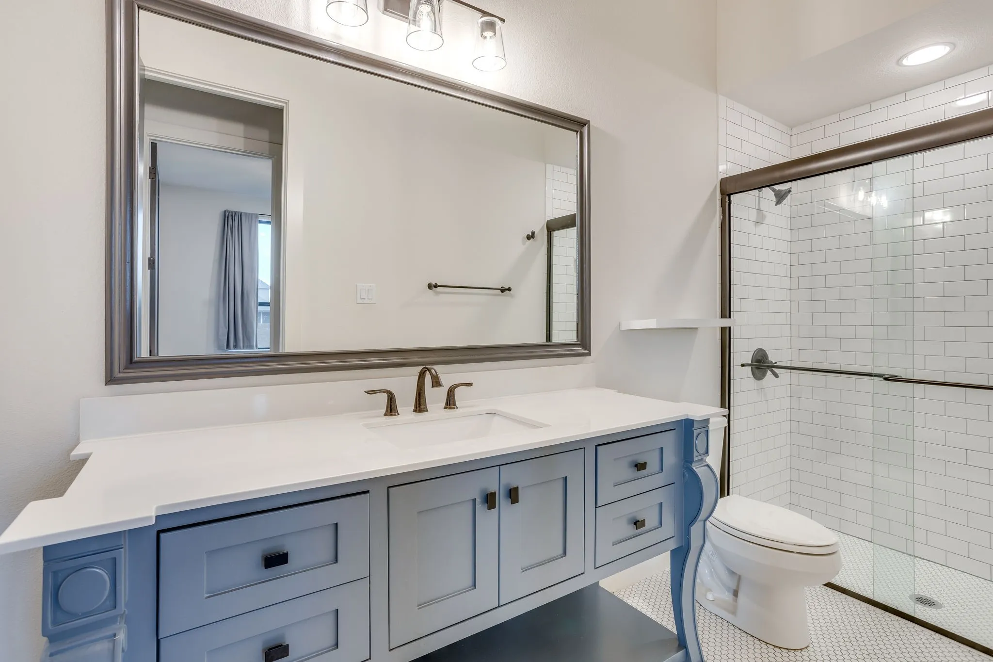 Bathroom vanity featuring a white countertop with integrated sink, bronze-finish faucet, and blue cabinetry