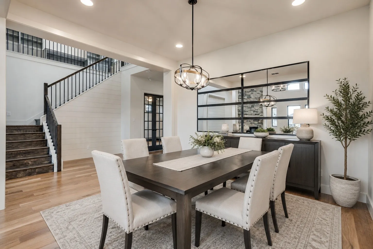 Dining area featuring wood-finish flooring, a contemporary chandelier, and an expansive decorative mirror. *Photo is virtually staged using AI.