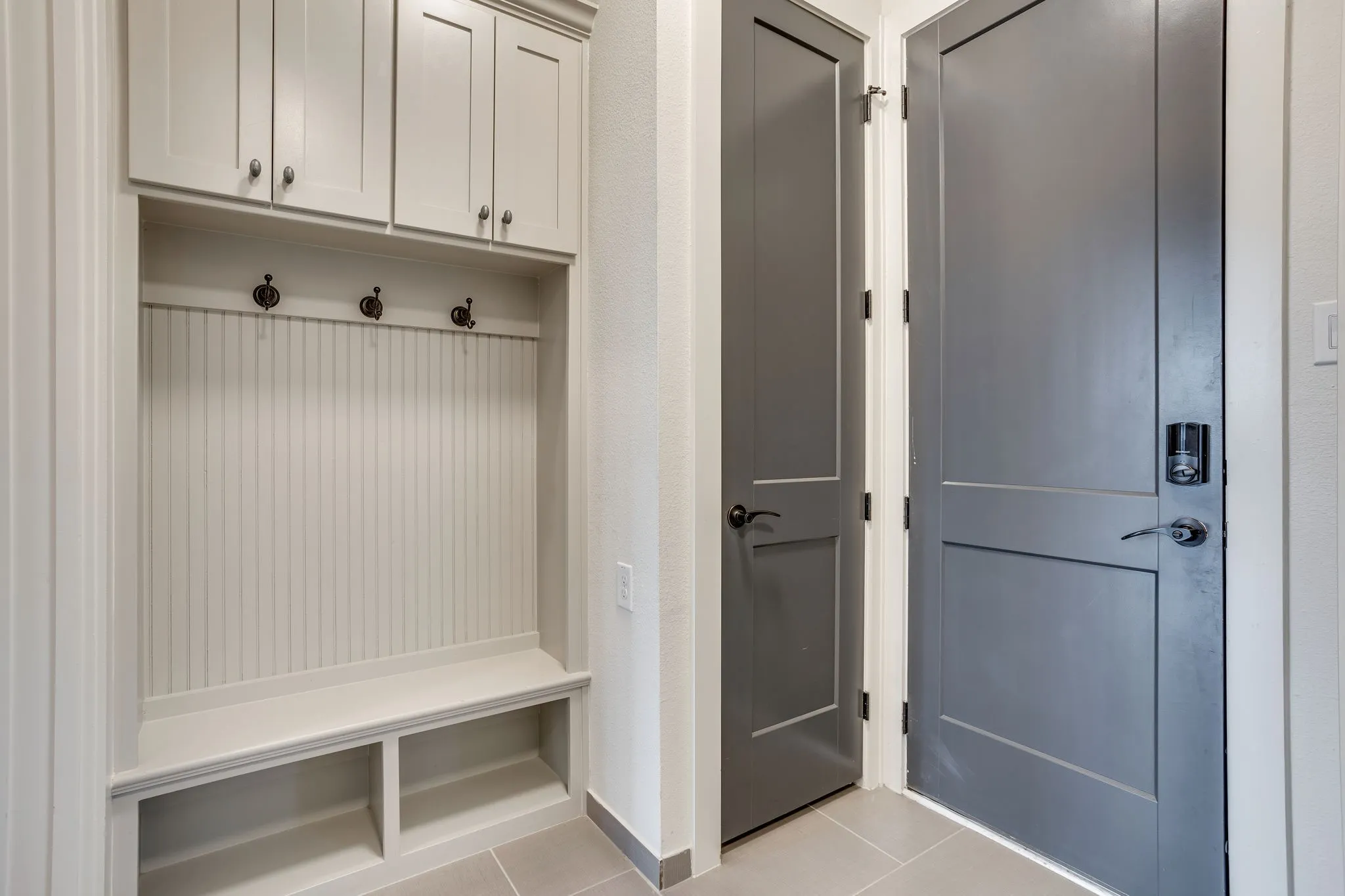 Built-in hall tree with beadboard backing, upper cabinetry, and storage cubbies
