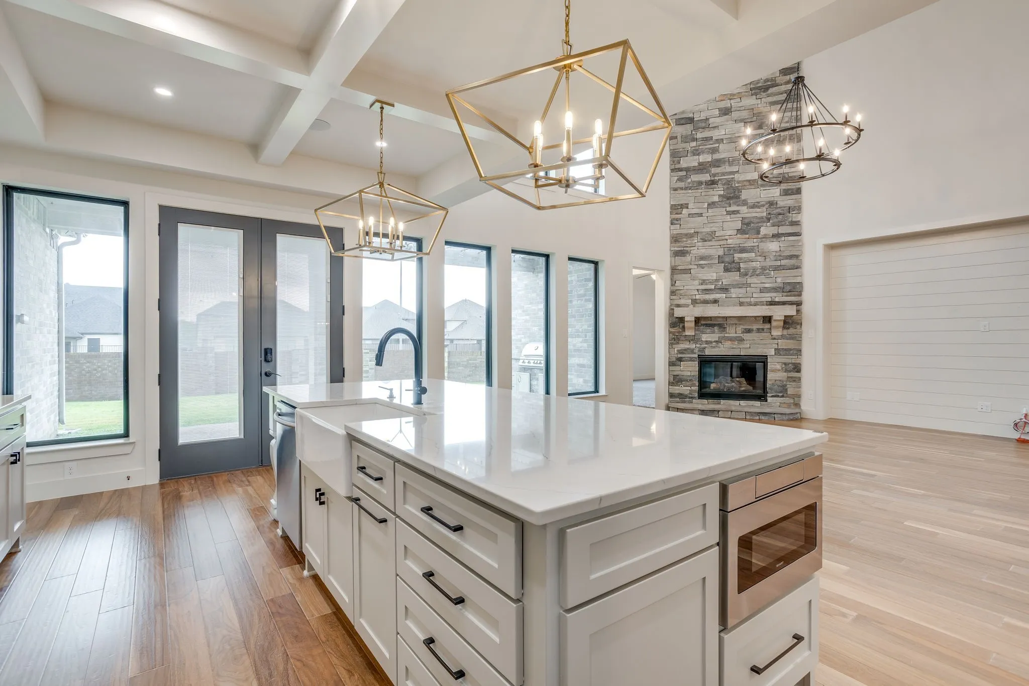 Spacious kitchen island with a white countertop and farmhouse sink, featuring a built-in microwave and ample cabinetry