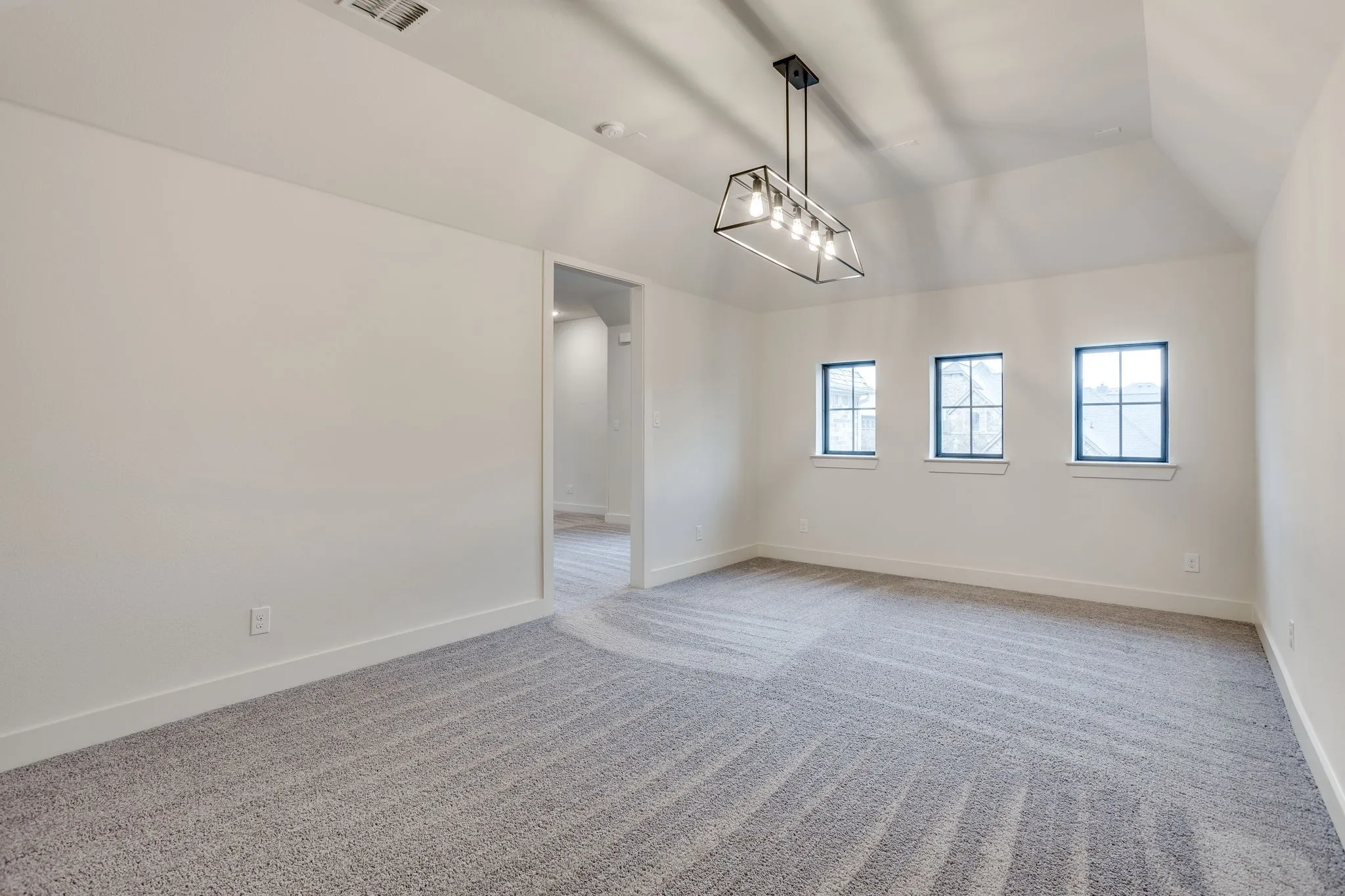 Spacious room featuring vaulted ceilings, a geometric chandelier, and three transom-style windows