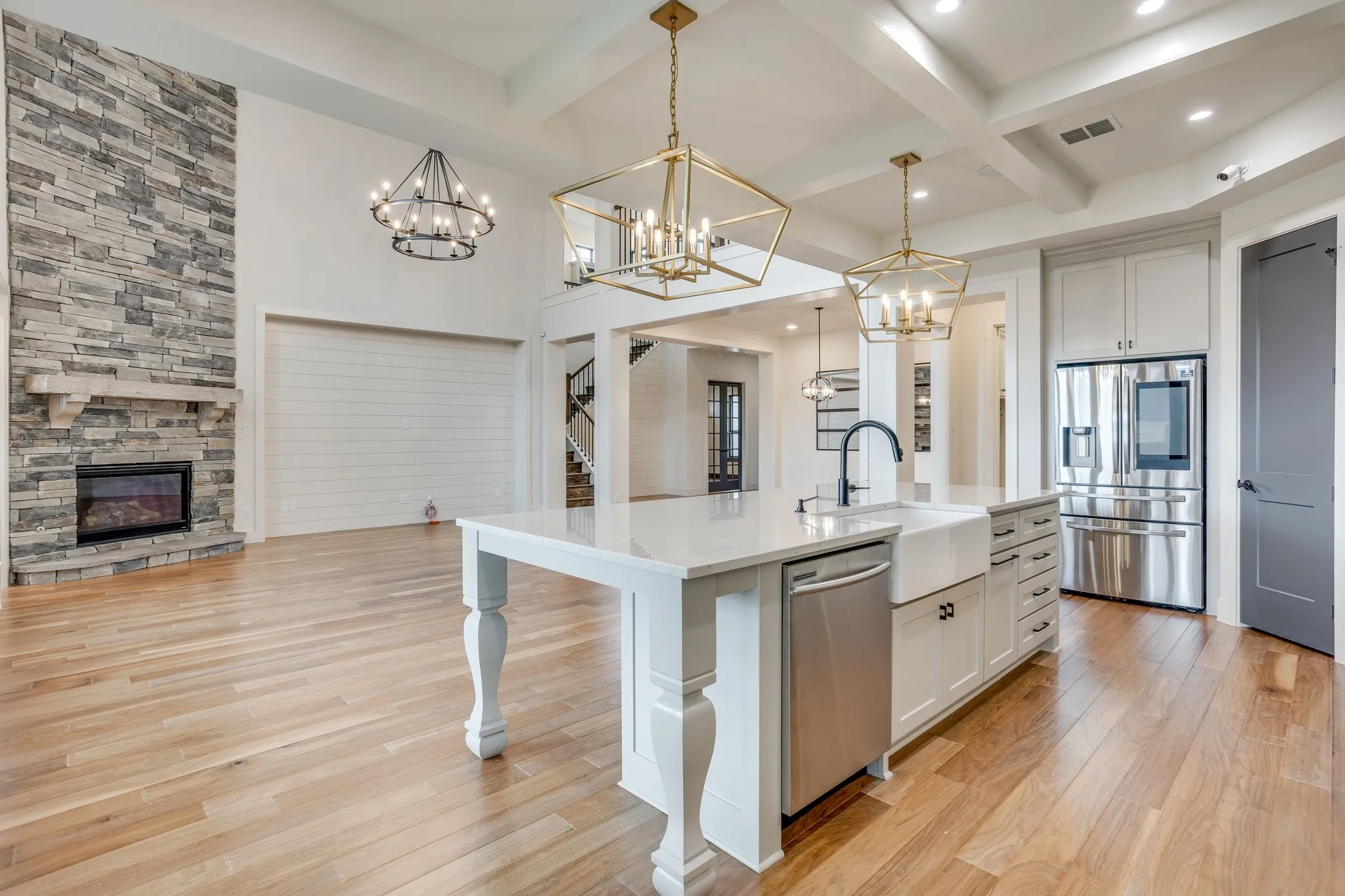 Gourmet kitchen with a large island featuring a farmhouse sink, stainless steel appliances, and white cabinetry