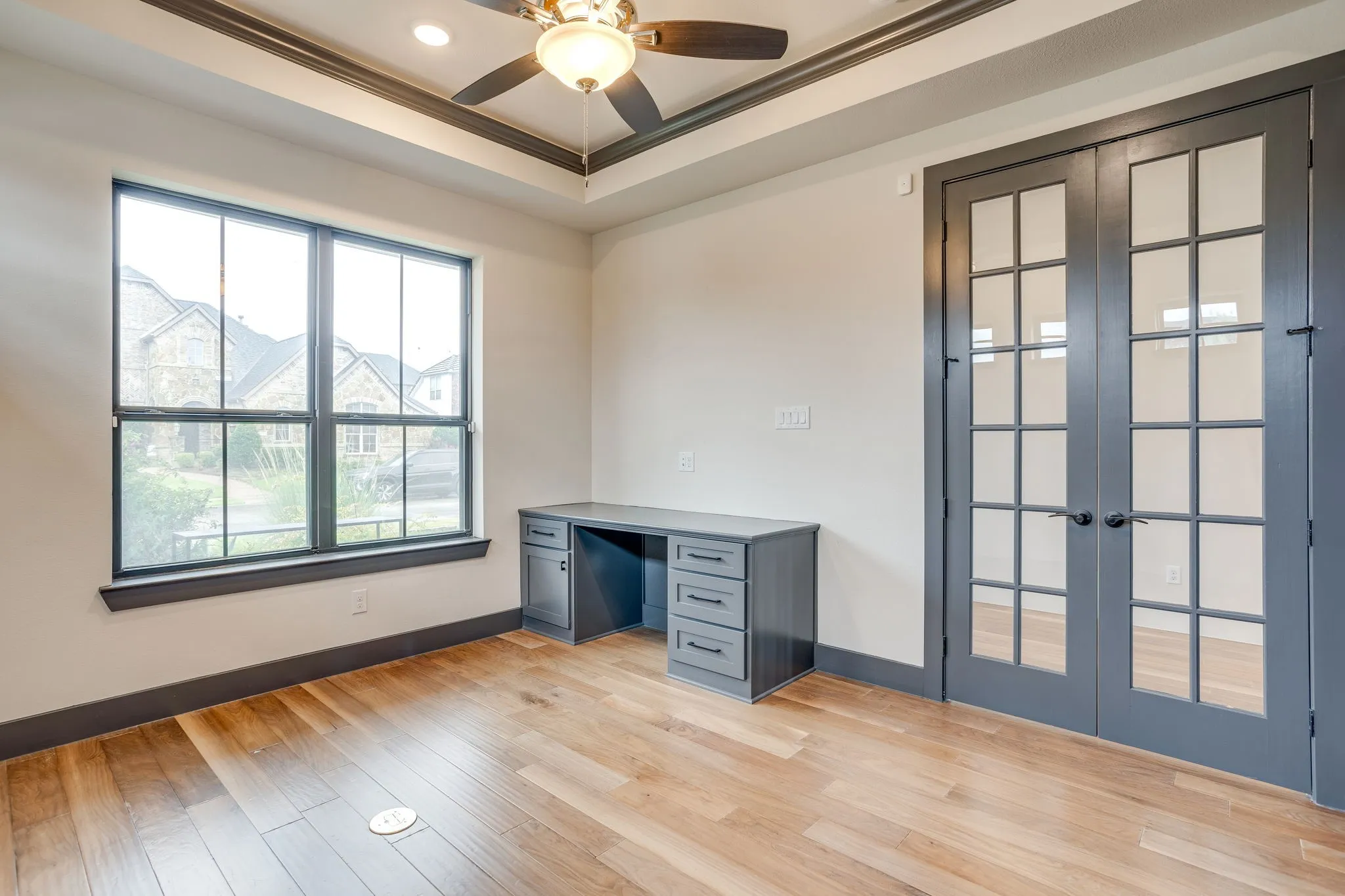 Room with wood-finish flooring, tray ceiling with recessed lighting and ceiling fan, and painted trim