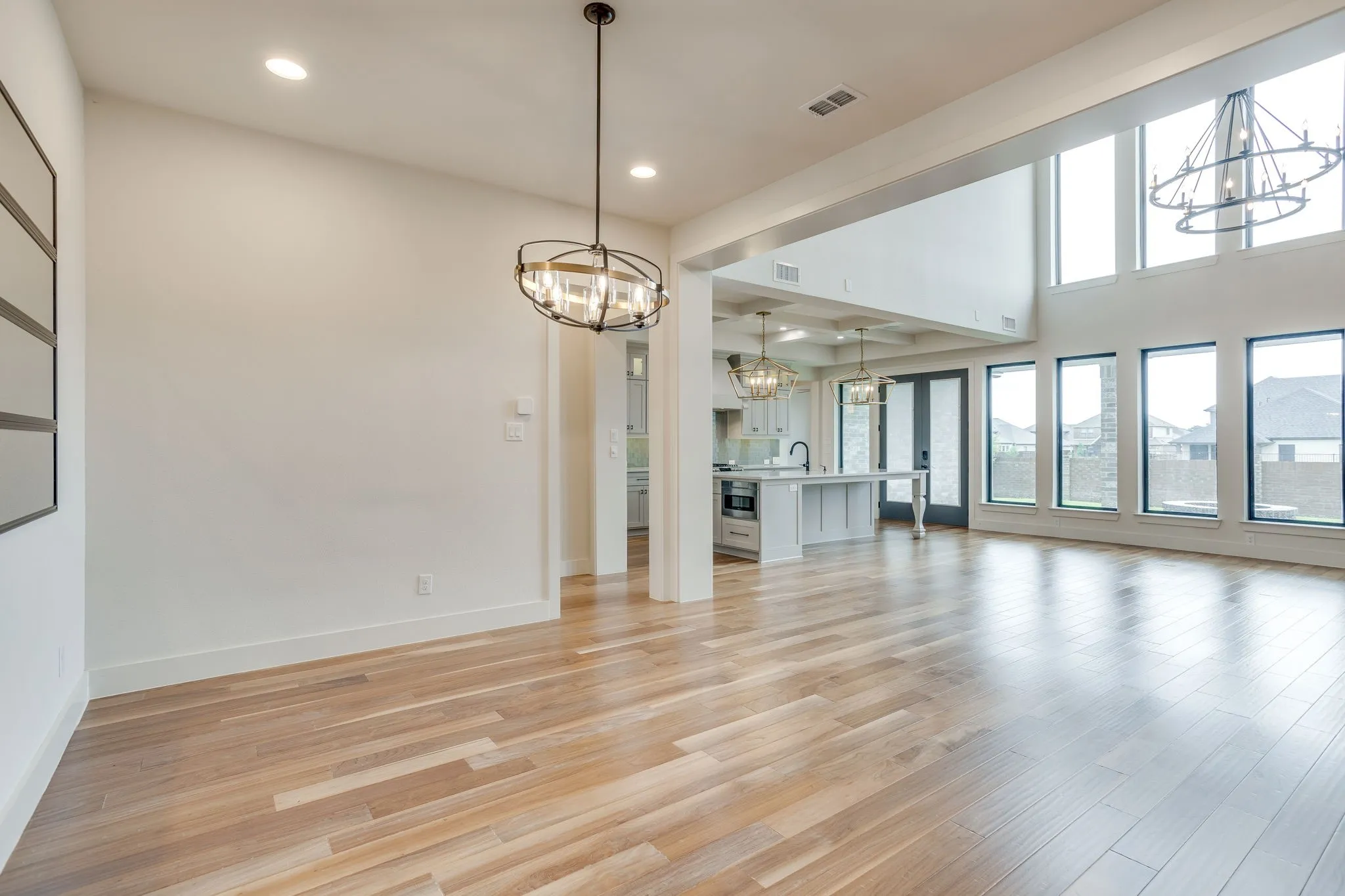 Expansive living area featuring light wood-finish flooring, soaring ceilings, and multiple large windows